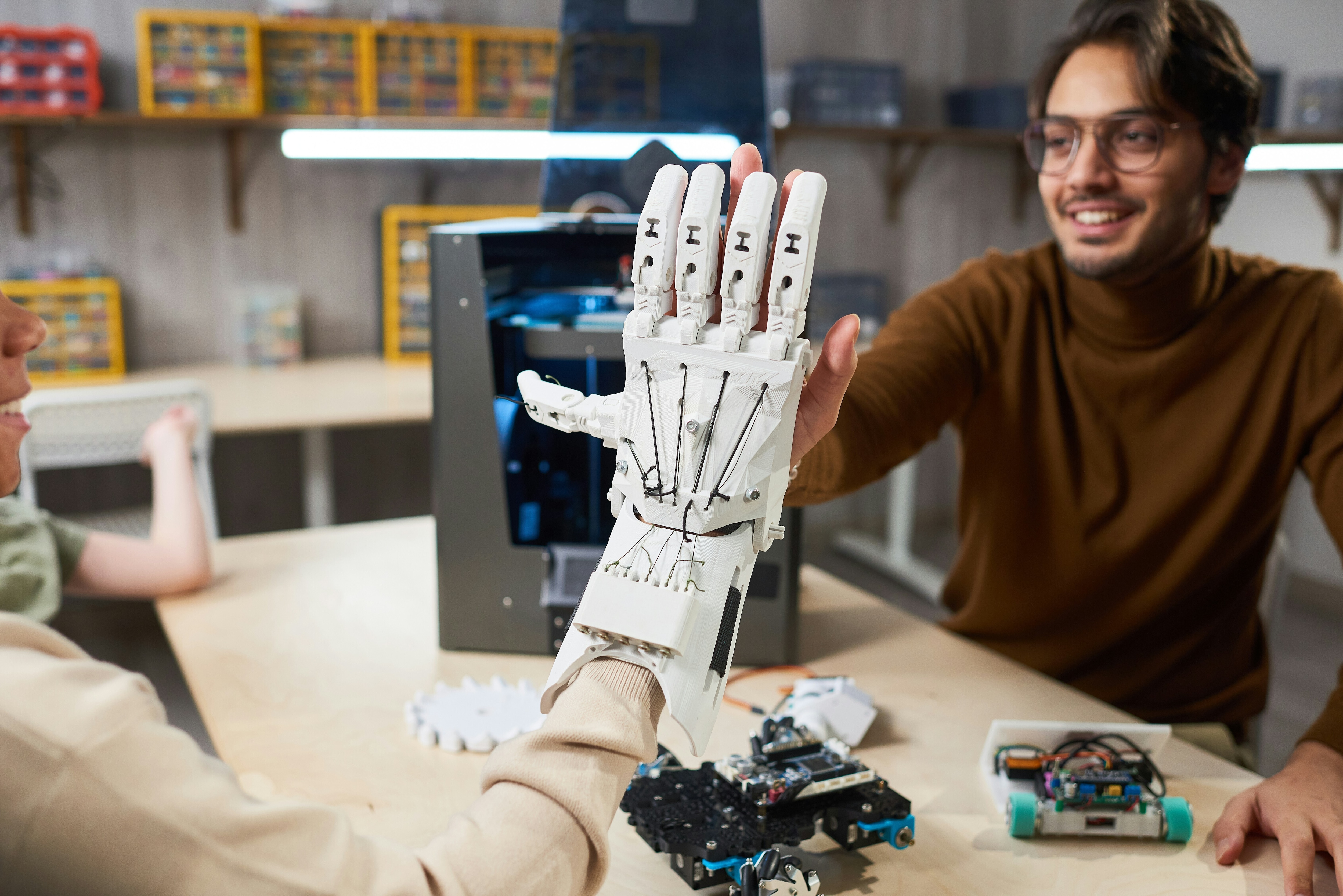 A man in a lab setting puts his hand against a robotic hand: Scaling innovation requires a supportive ecosystem