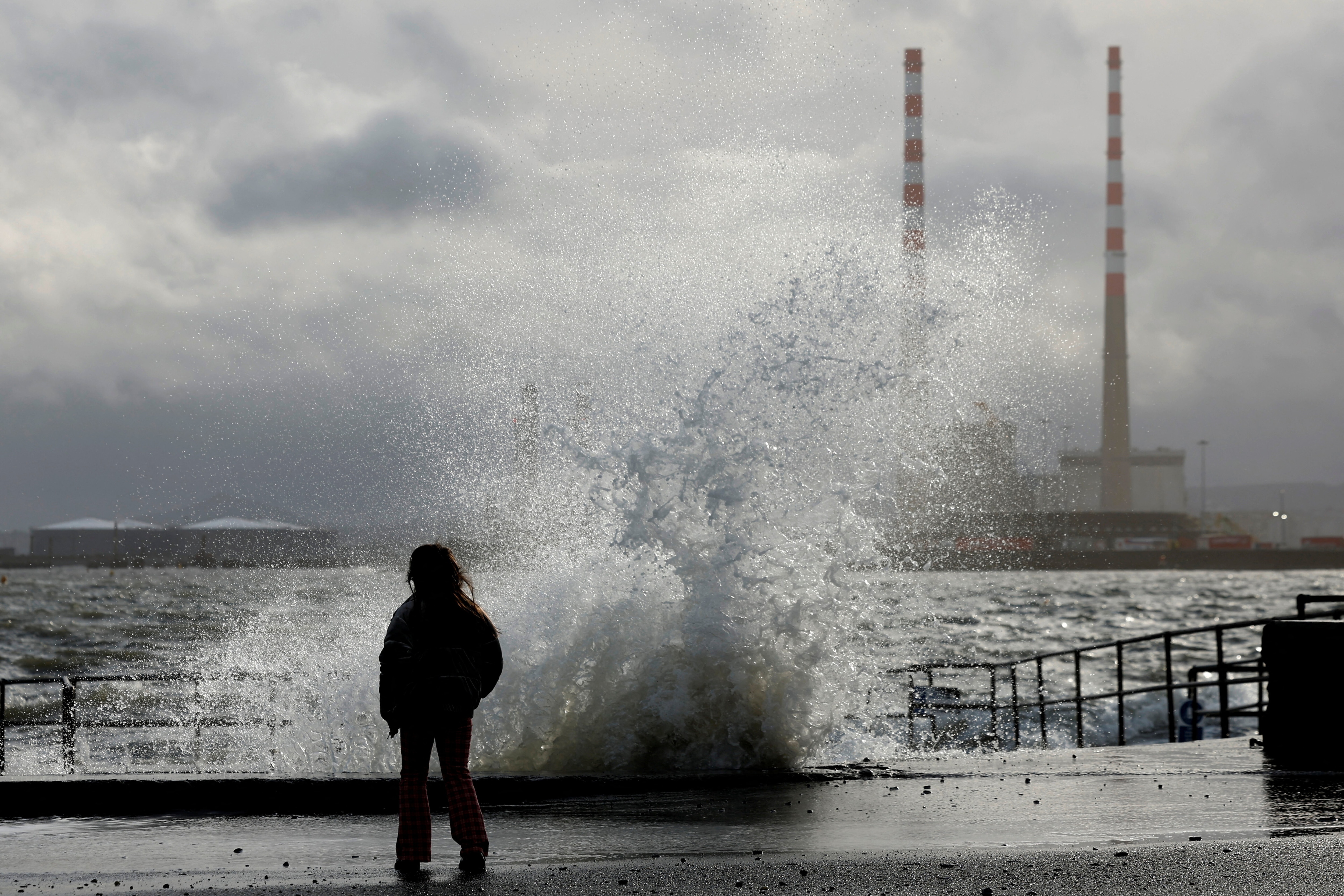 A child stands looking at a wave overtopping on Clontarf promenade during stormy weather with high winds, in Dublin, Ireland, January 20, 2026. REUTERS/Clodagh Kilcoyne