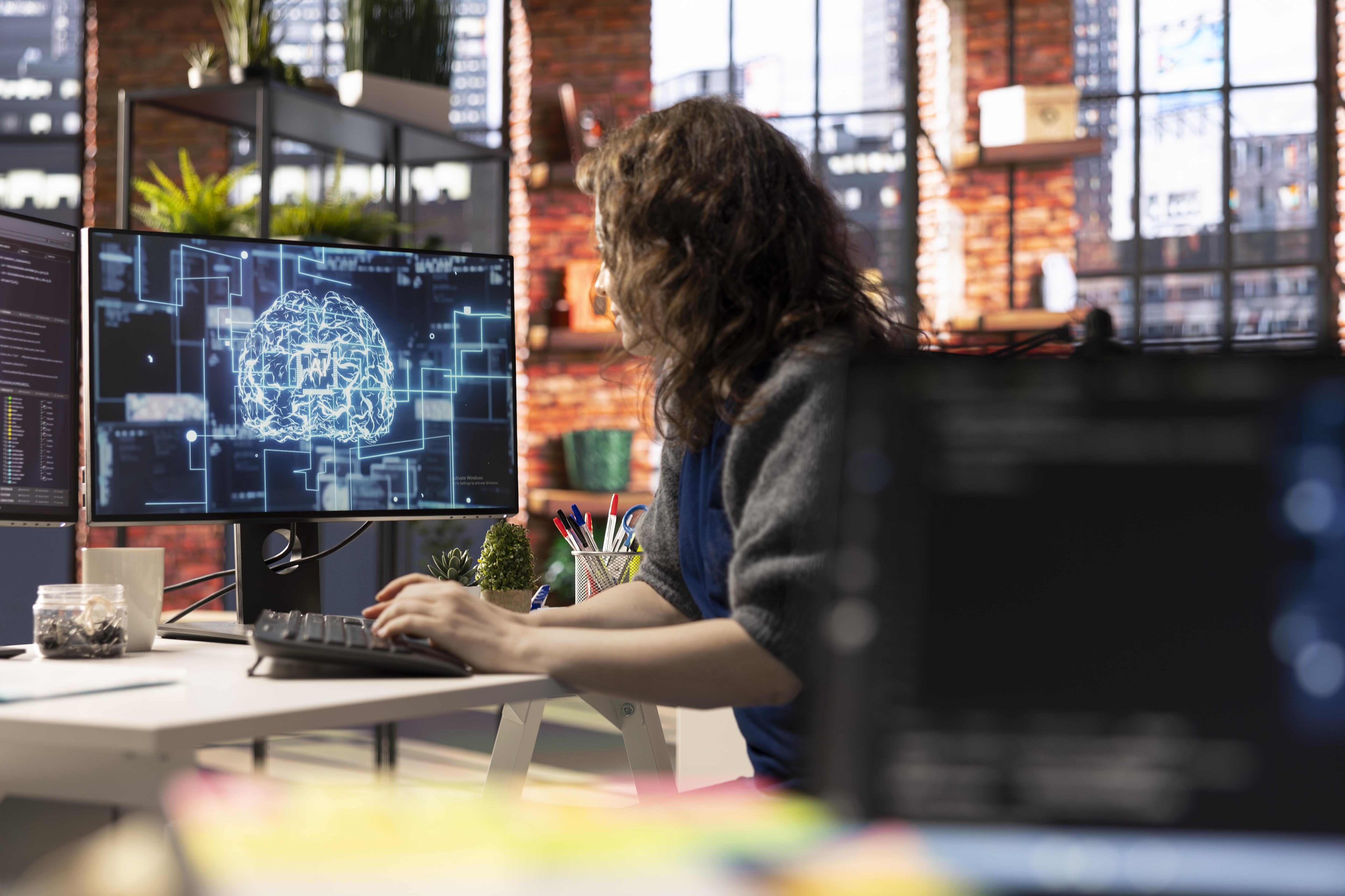 Teleworking developer using computer for artificial intelligence computing through self learning algorithms. Agency IT engineer works with AI deep neural networks on desktop PC.