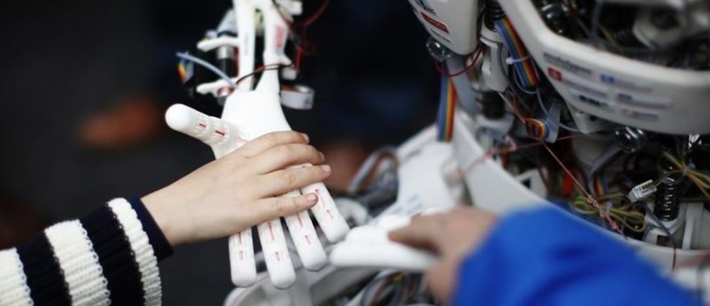 Children touch the hands of the humanoid robot Roboy at the exhibition Robots on Tour in Zurich, March 9, 2013. A project team composed of scholars and industry representatives developed the prototype of the tendon driven humanoid robot Roboy within nine months.  Roboy was unveiled to the public today during the exhibition that is marking the 25th anniversary of the Artificial Intelligence Laboratory of the University of Zurich (AI Lab). REUTERS/Michael Buholzer (SWITZERLAND - Tags: SCIENCE TECHNOLOGY SOCIETY BUSINESS) - BM2E93916AH01