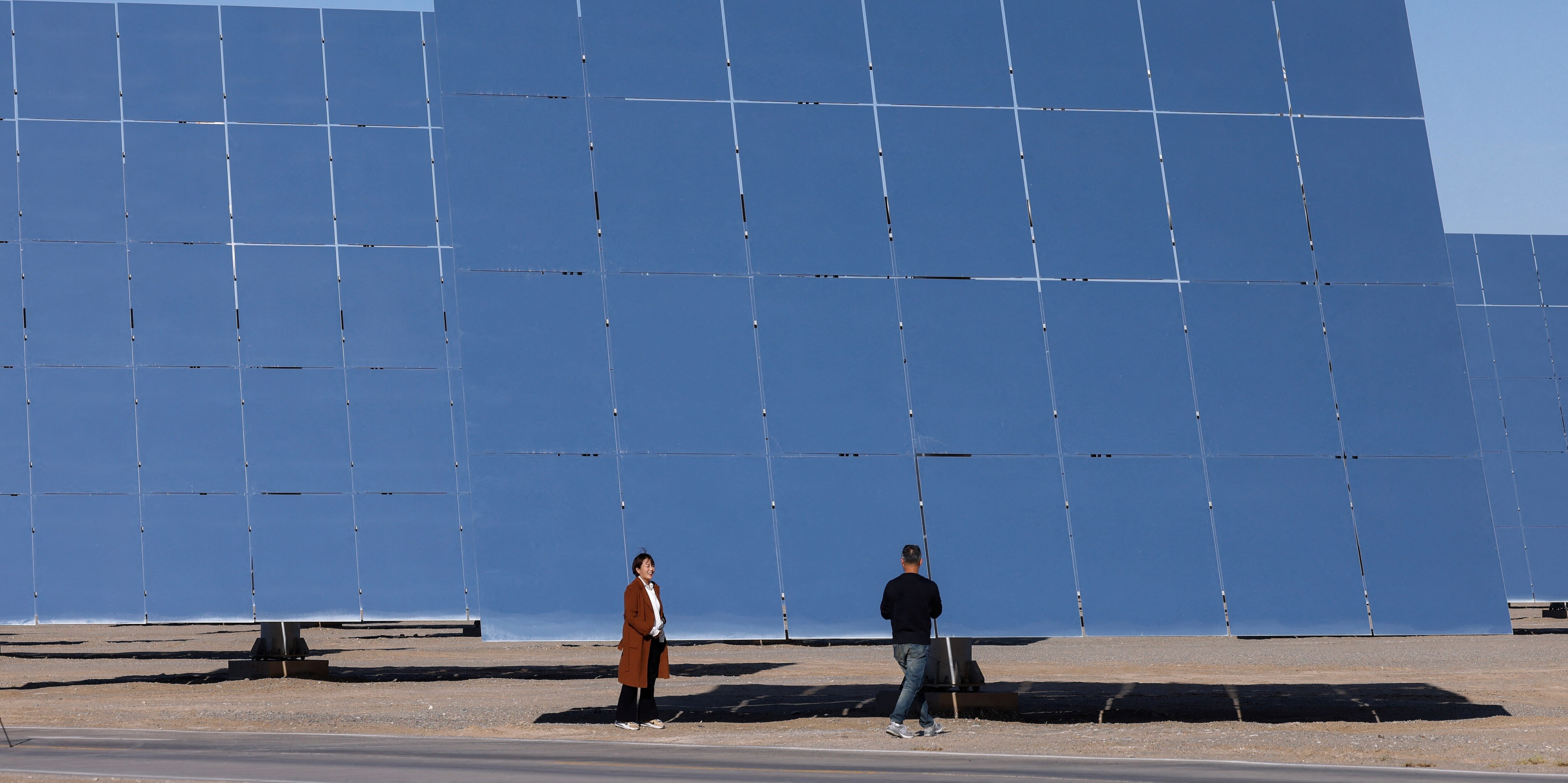 Periodistas trabajan junto a los espejos heliostáticos en las instalaciones del proyecto de generación de energía solar térmica Dunhuang Shouhang 100 MW Tower, durante una visita organizada para los medios de comunicación al parque industrial fotovoltaico de Dunhuang, en la provincia de Gansu (China), el 16 de octubre de 2024.