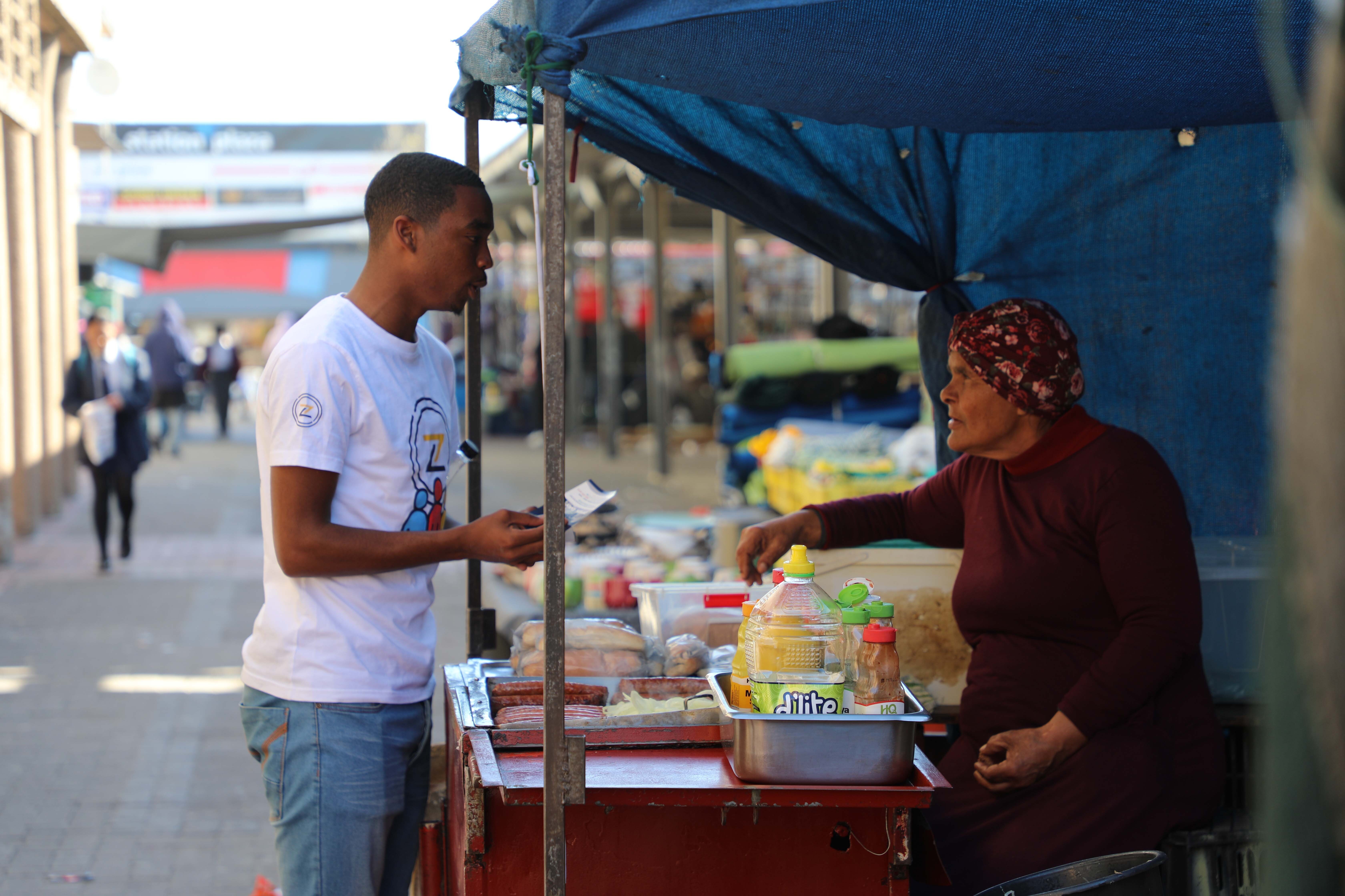 Man paying at a street food cart: Zlto – founded by one of today's young social innovators – tackles youth unemployment by rewarding community engagement and skill-building with a digital currency