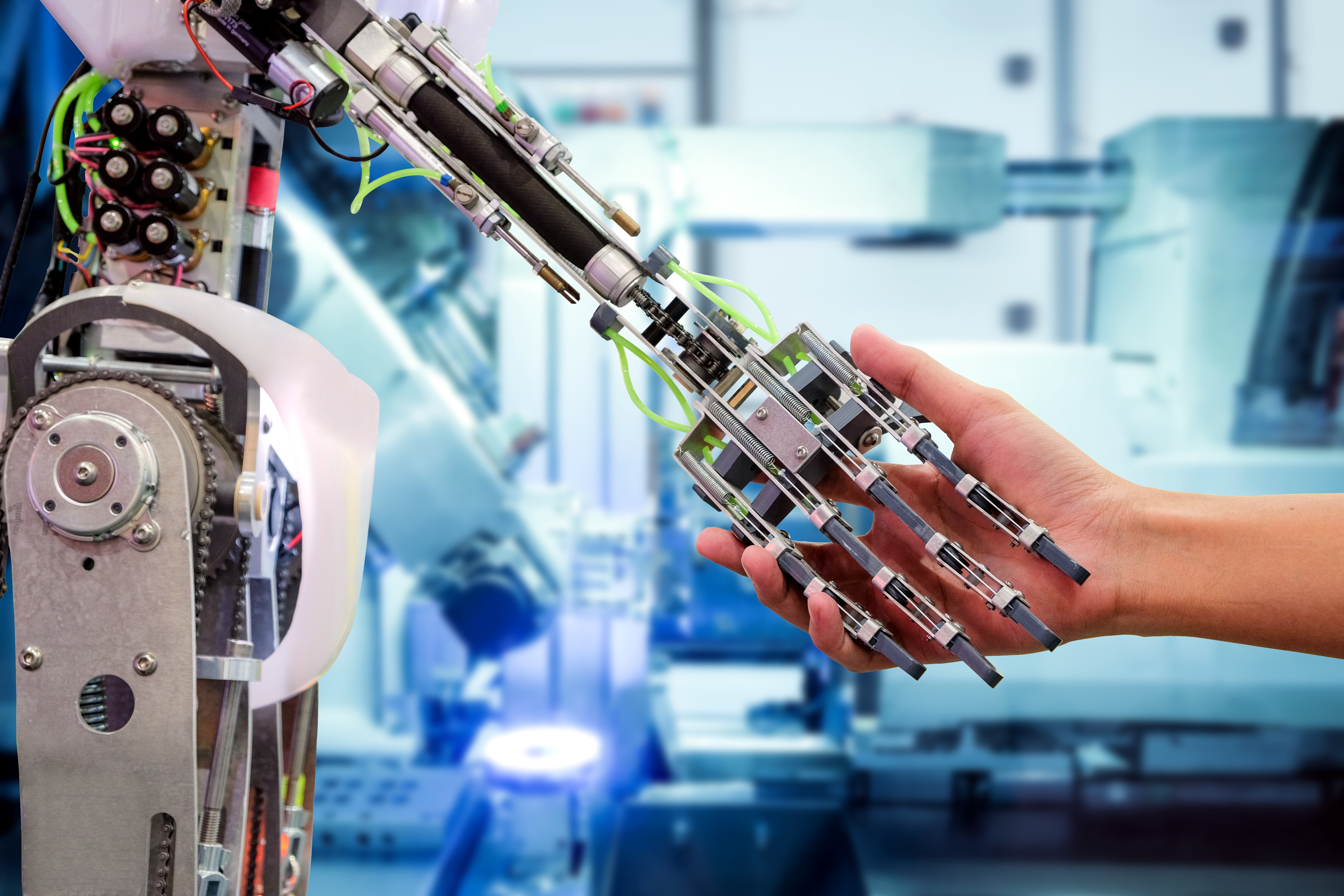 Artificial Intelligence (AI) handshake with humans on industrial robotics in blue tone color blurred background, The robot has a role to work replacing humans in modern industries, industry 4.0 concept