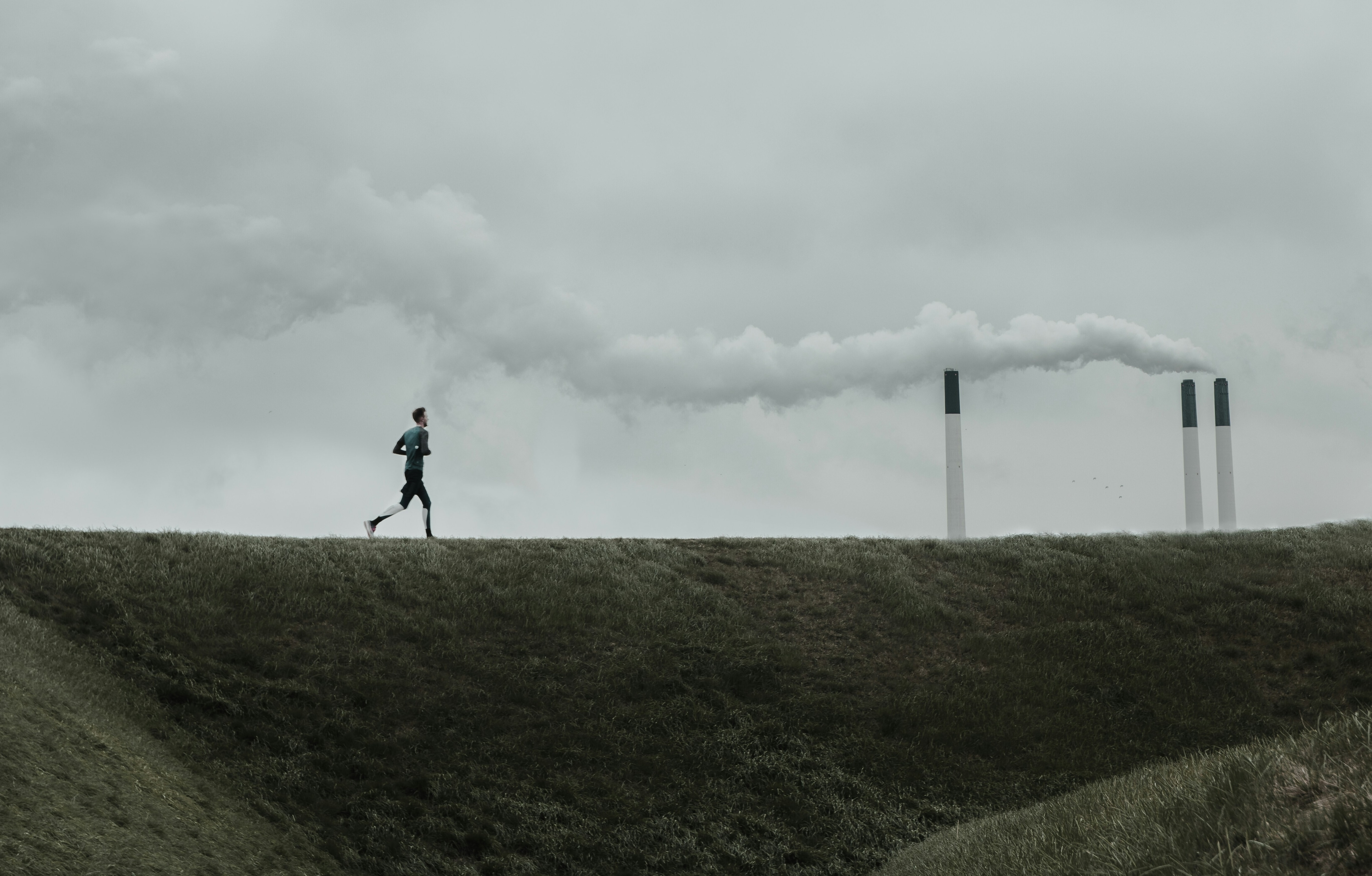 A man running in front of three smoke stacks: Europe’s climate policy must think about carbon markets more holistically