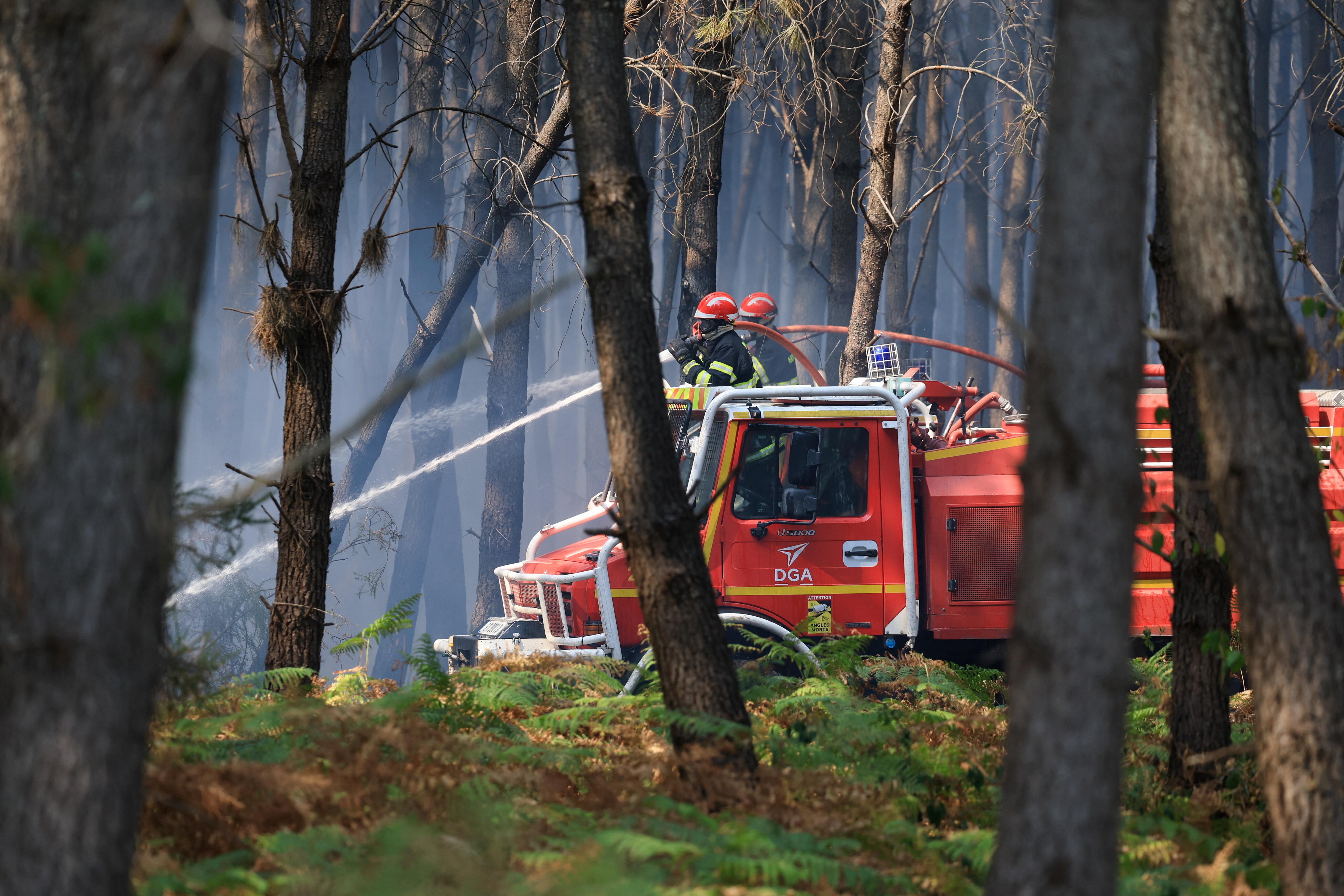 Firefighters work to extinguish a reigniting fire in Le Temple, Gironde department, amid drought conditions following a heatwave and water shortages across much of France.