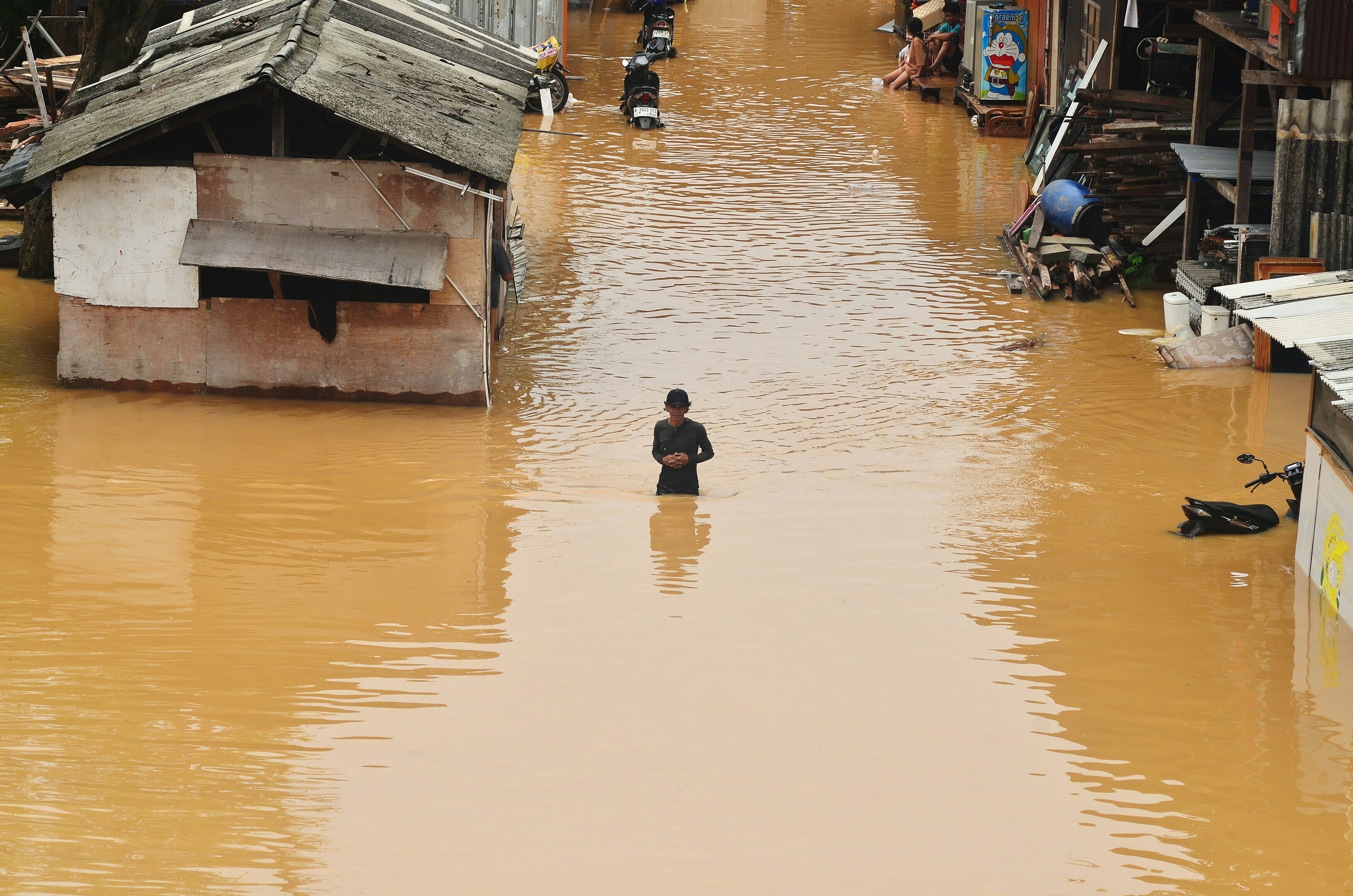 A person walking through a flooded street, illustrating the need for insurance to protect against climate damage