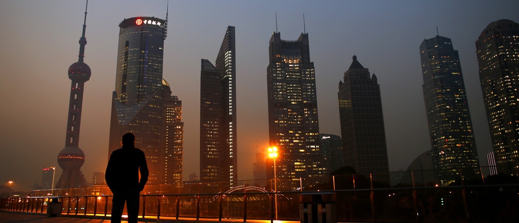 A man looks at the Pudong financial district of Shanghai November 20, 2013. With a shift in tone and language, China's central bank governor has dangled the prospect of speeding up currency reform and giving markets more room to set the yuan's exchange rate as he underlines broader plans for sweeping economic change. The central bank under Zhou Xiaochuan has consistently flagged its intention to liberalise financial markets and allow the yuan to trade more freely, even before the Communist Party's top brass unveiled late last week the boldest set of economic and social reforms in nearly three decades.   REUTERS/Carlos Barria (CHINA - Tags: BUSINESS CITYSCAPE TPX IMAGES OF THE DAY) - GM1E9BK1FE701