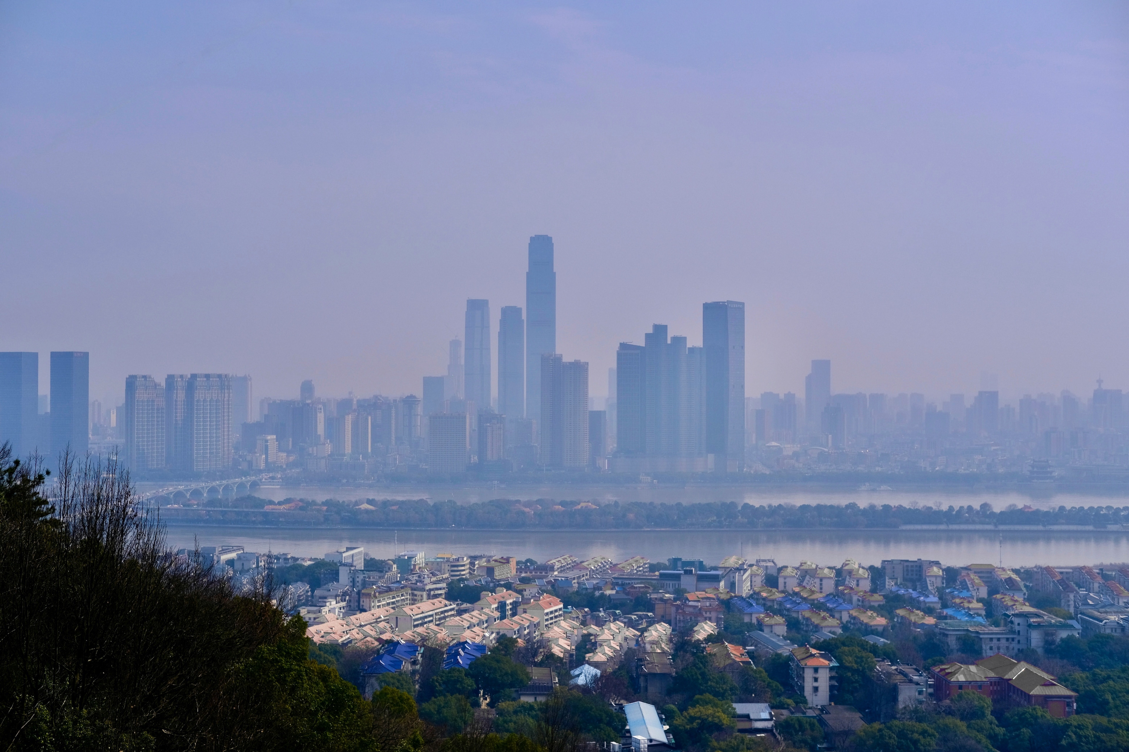 A cityscape in front of a river with immense smog (Changsha, Hunan, China): Air and water pollution are interconnected wicked problems that cities can help address