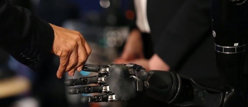 U.S. President Barack Obama touches a robotic arm operated by Nathan Copeland, a quadriplegic brain implant patient who can experience the sensation of touch and control a remote robotic arm with his brain during a tour of the innovation projects at the White House Frontiers conference in Pittsburgh, U.S. October 13, 2016.  REUTERS/Carlos Barria