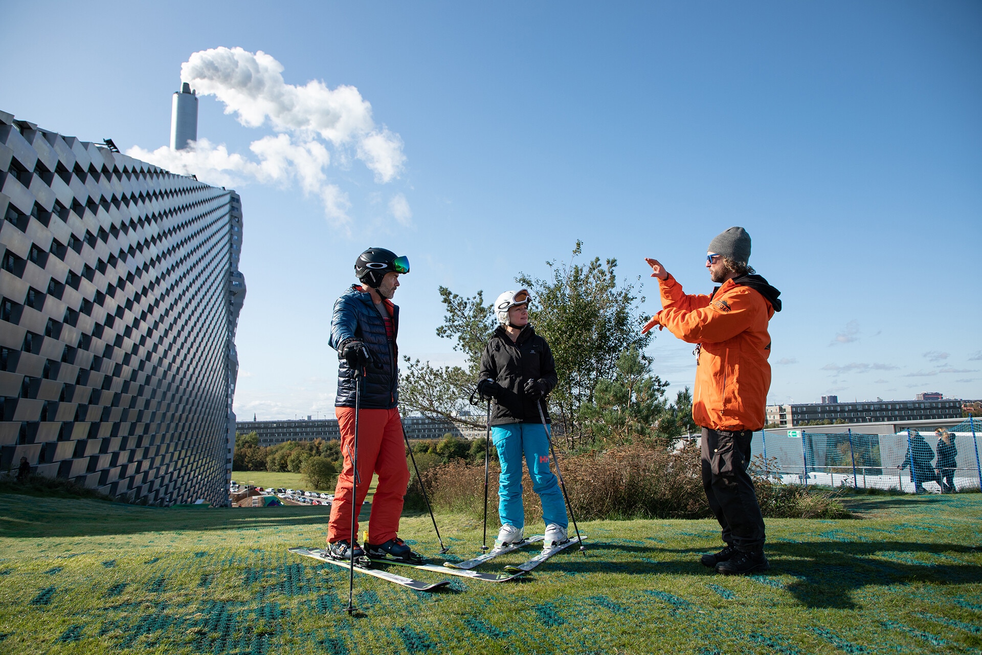 Three men on skis in front of the Copenhill waste-to-energy plant