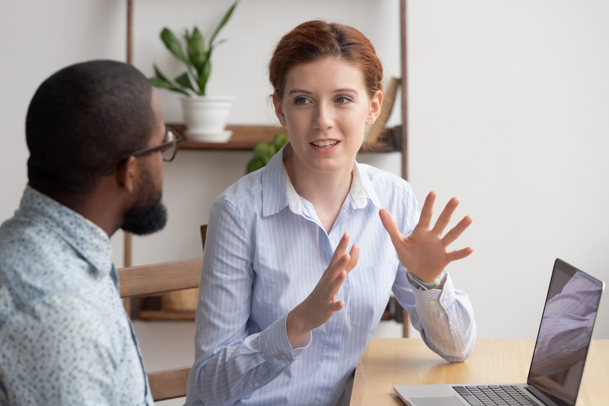 Two diverse businesspeople chatting sitting behind laptop in office: Sensitive organizations sense what their customers need