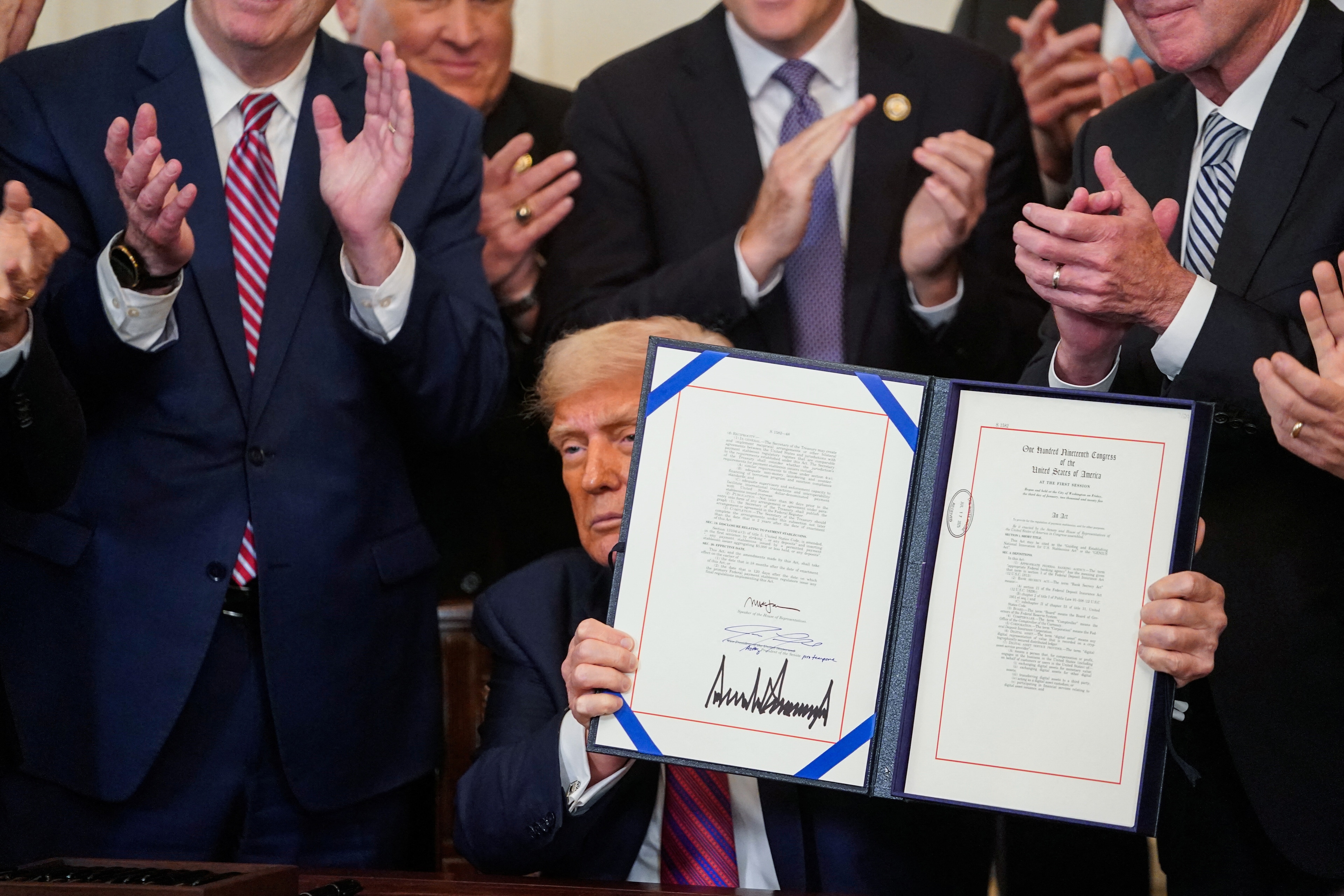 US President Donald Trump holds the signed Genius Act, which will develop regulatory framework for stablecoin cryptocurrencies and expand oversight of the industry, at the White House in Washington, D.C., U.S., July 18, 2025. REUTERS/Nathan Howard