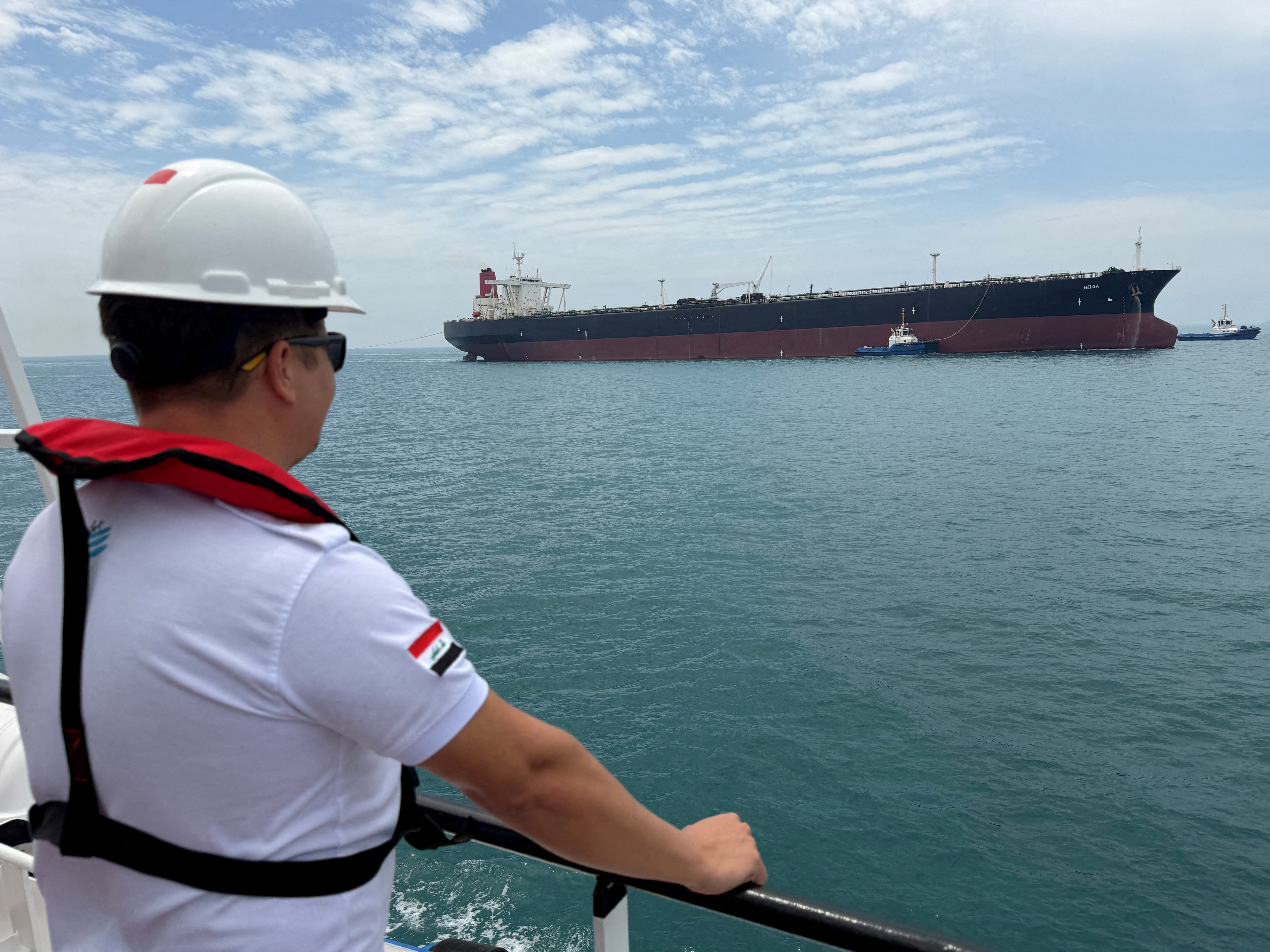 FILE PHOTO: A sailor observes the oil tanker HELGA, which is moored at one of Iraq's southern offshore oil terminals near Basra, as it prepares to load crude oil, becoming the second vessel to arrive since the closure of the Strait of Hormuz, April 24, 2026. Picture taken with a mobile phone. REUTERS/Mohammed Aty/File Photo/File Photo