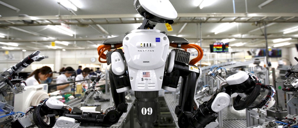 A humanoid robot works side by side with employees in the assembly line at a factory of Glory Ltd., a manufacturer of automatic change dispensers, in Kazo, north of Tokyo, Japan, July 1, 2015. 