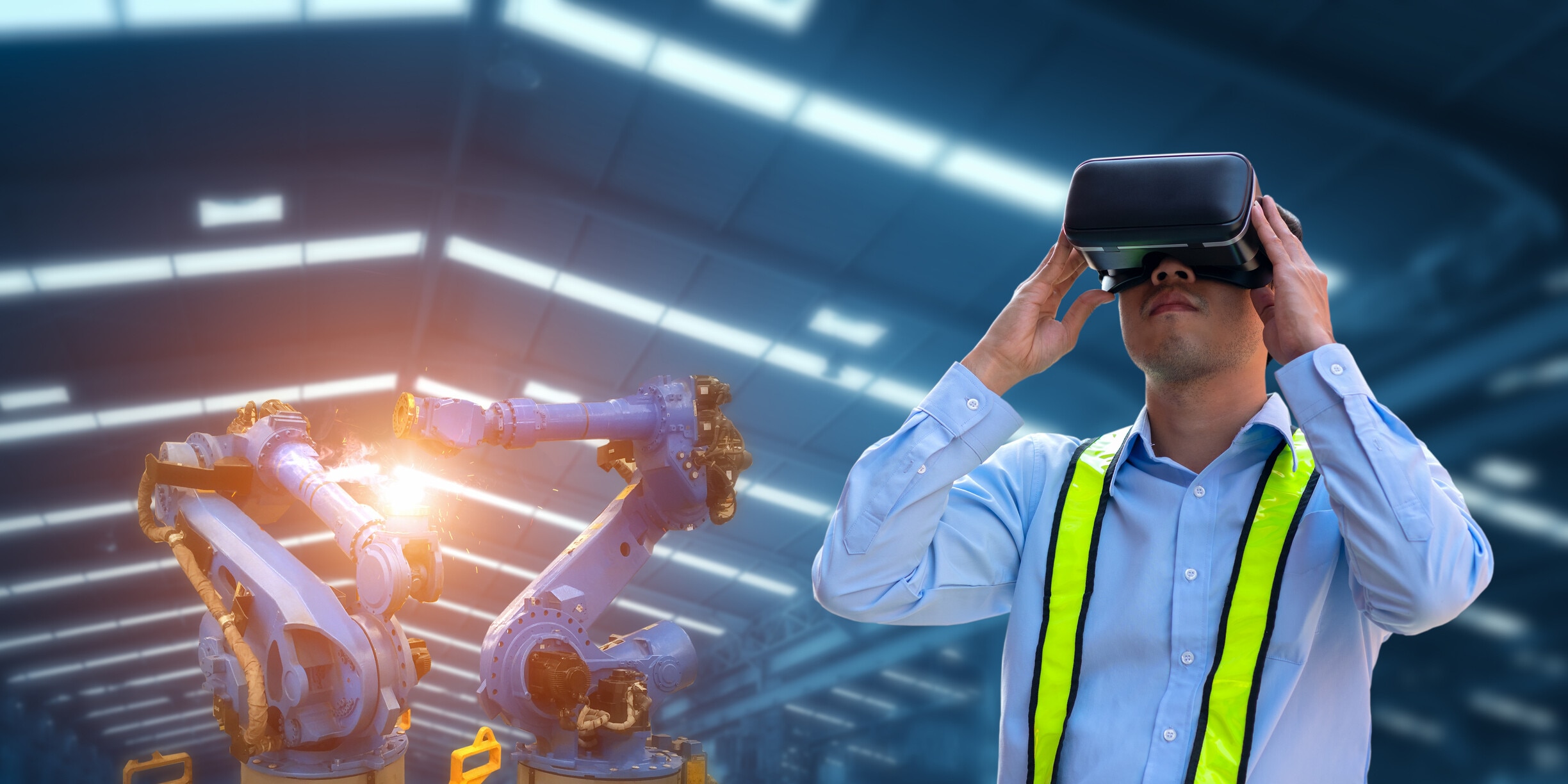 Businessman using VR Glasses for virtual reality and robot welding machines, automatic mechanical arms, modern industrial factories.Industry 4.0; AI era