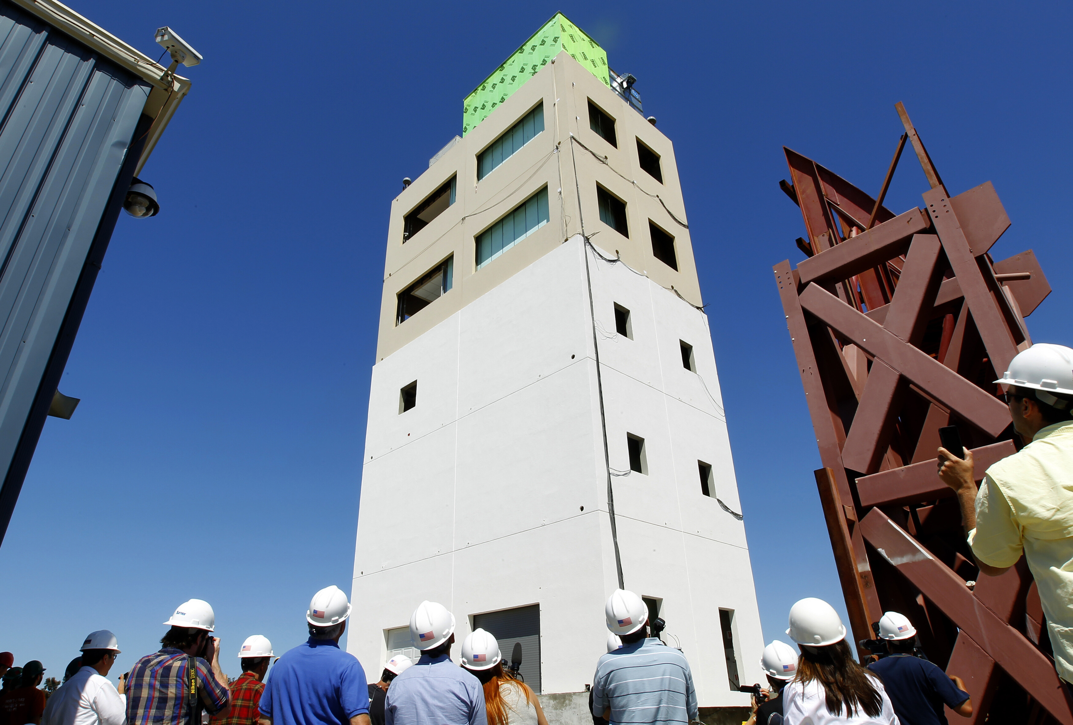 Engineers and members of the media stand next to a specially constructed five-storey building during an earthquake test in San Diego, California April 17, 2012: Investment in urban resilience and disaster preparedness is improving insurance premiums