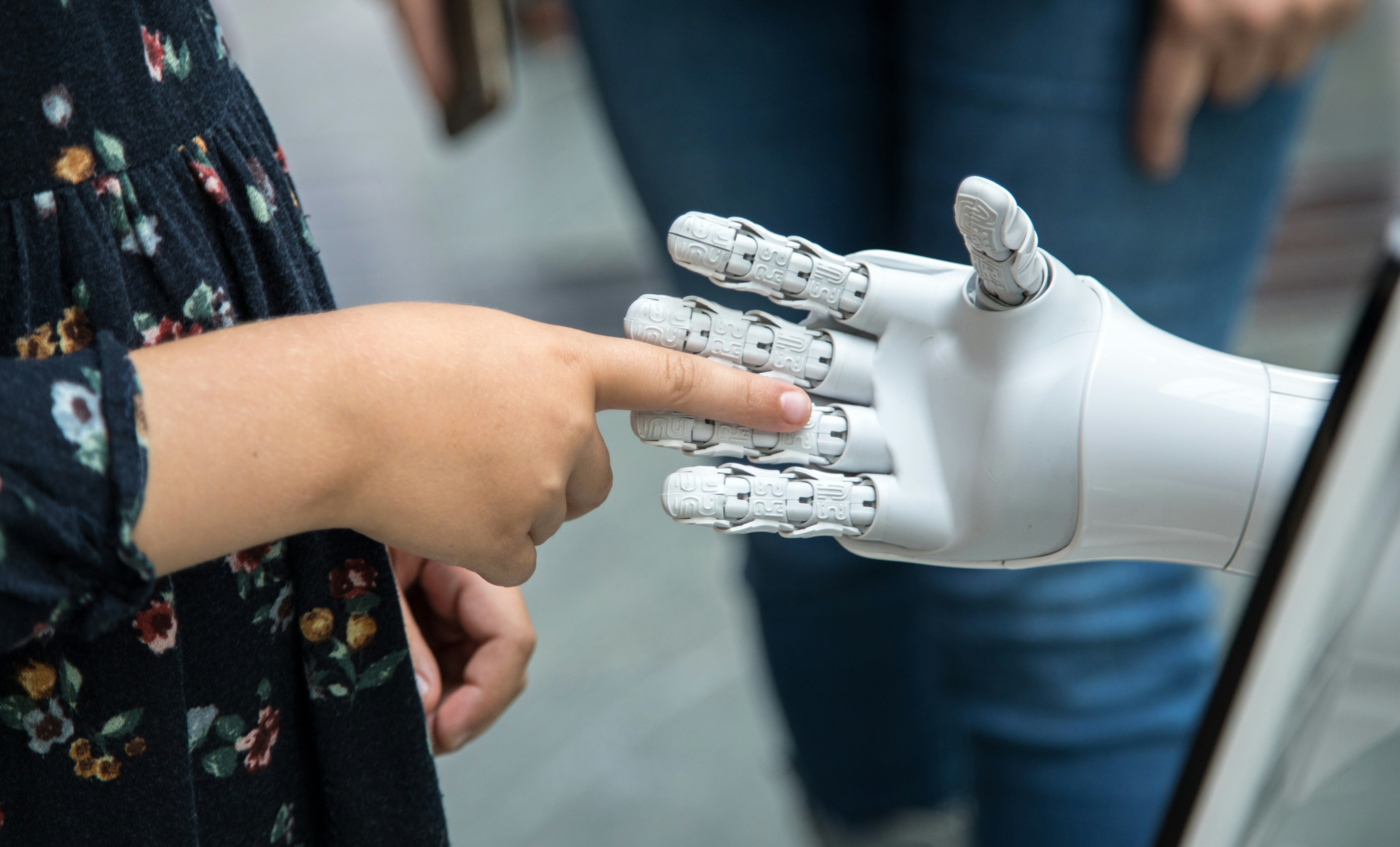 A woman touches a robot hand.