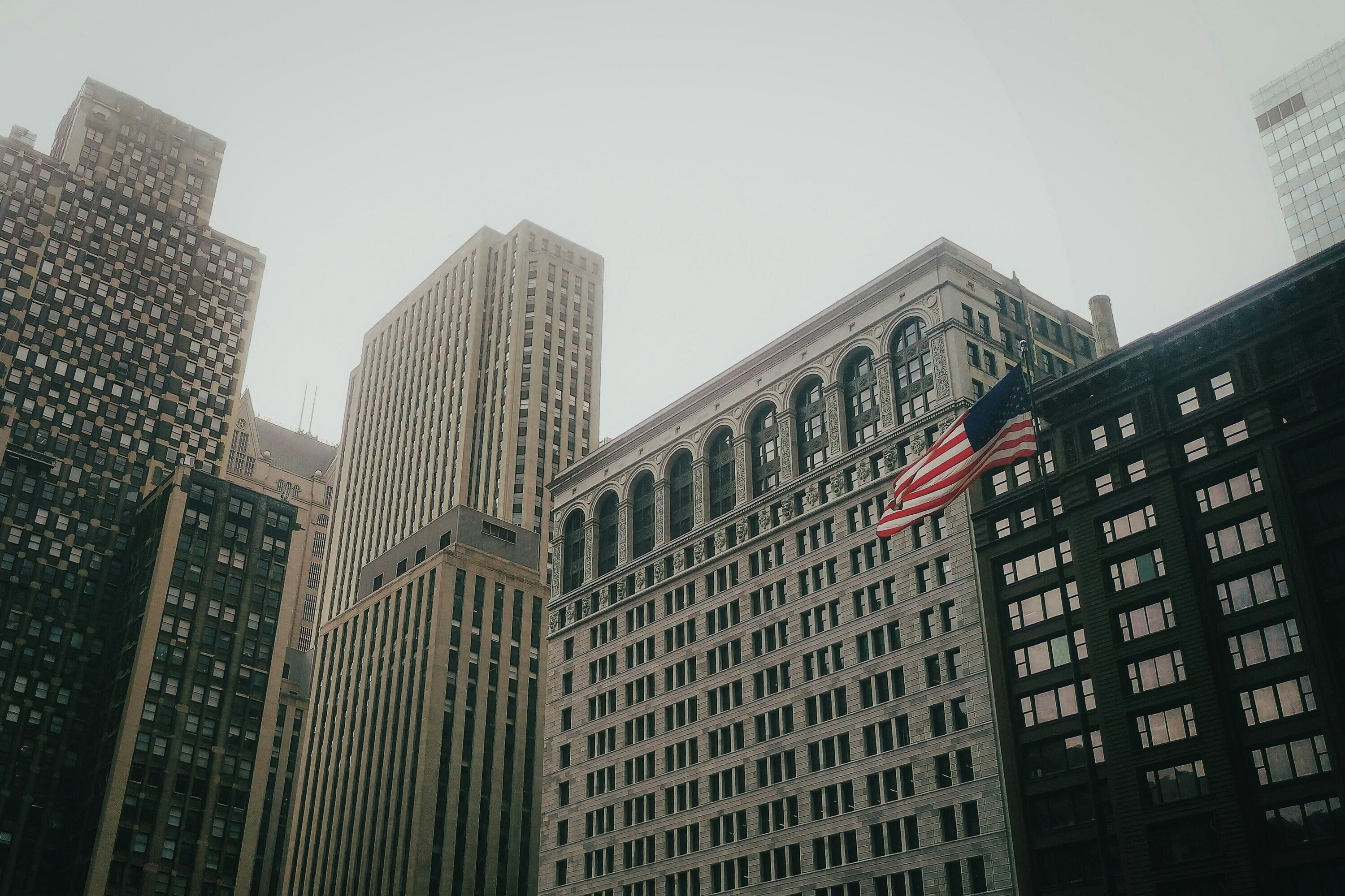 An American flag amid city skyscrapers and buildings: US business leaders can create value amid geopolitical tensions.