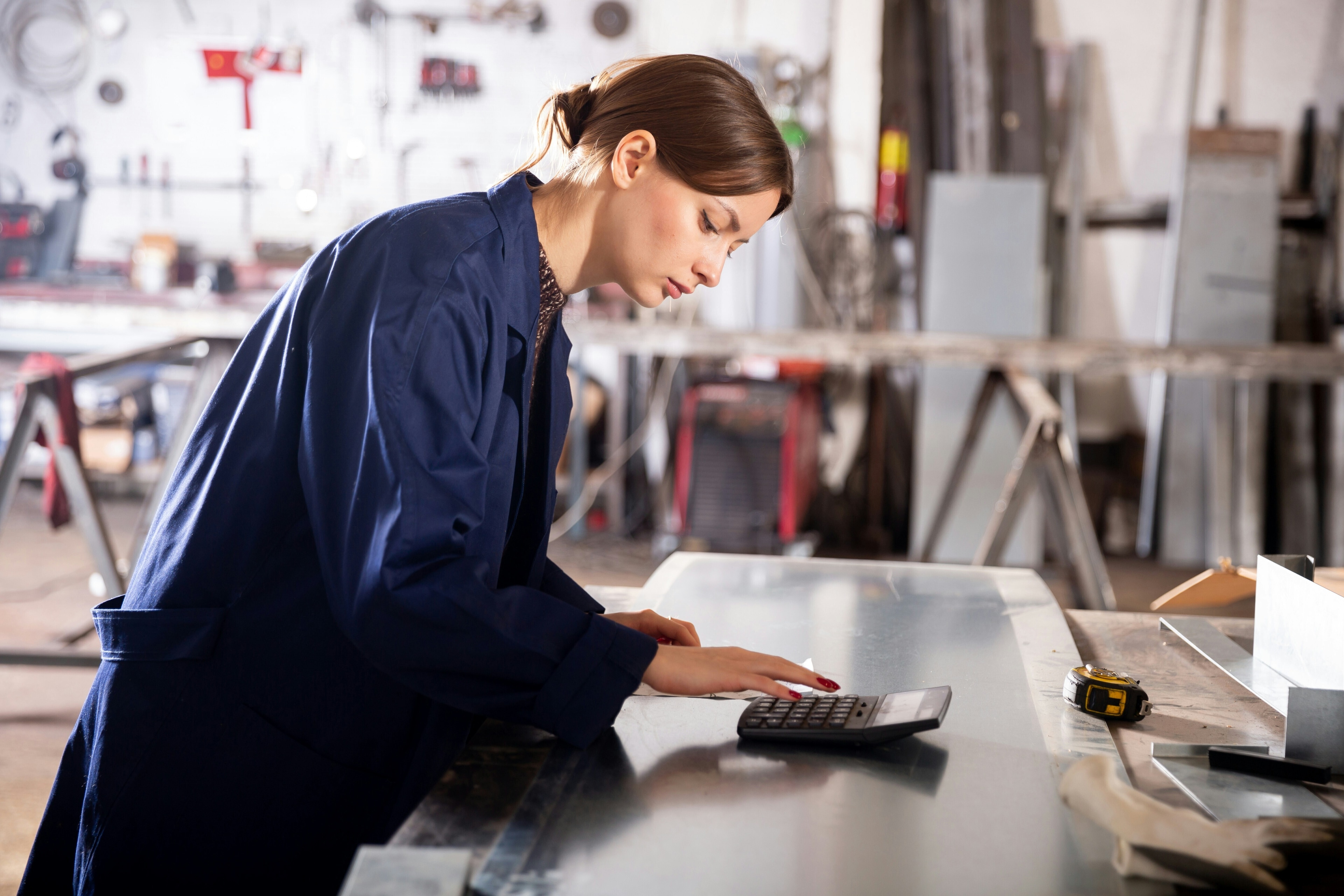 Woman in overalls uses calculator: Transformation in manufacturing often fails due to poor communication