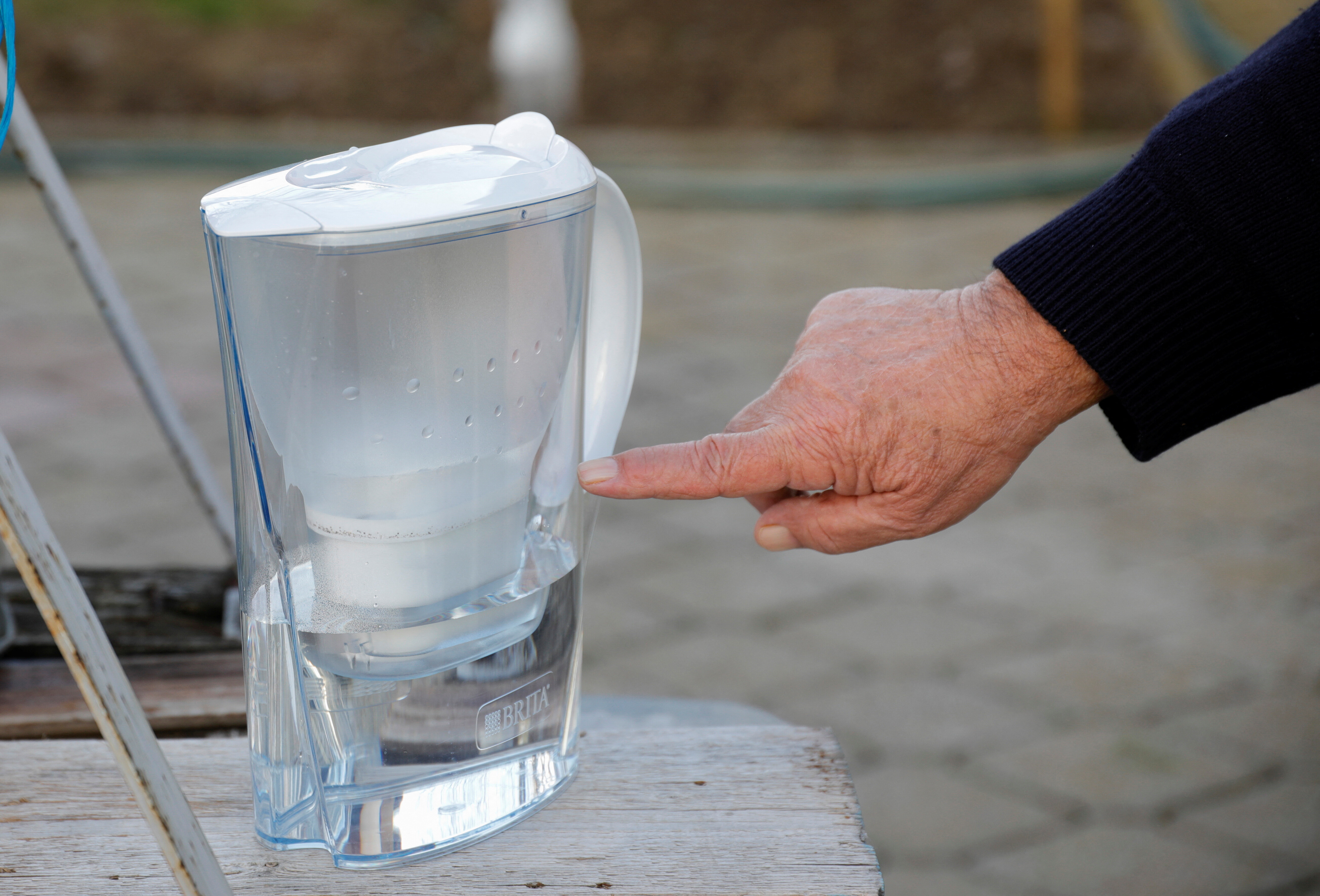Fatmir Selmani, a resident of the village of Lojane, uses a jug with a water filter, to clean the water from the well in front of his house, in Lojane, North Macedonia.