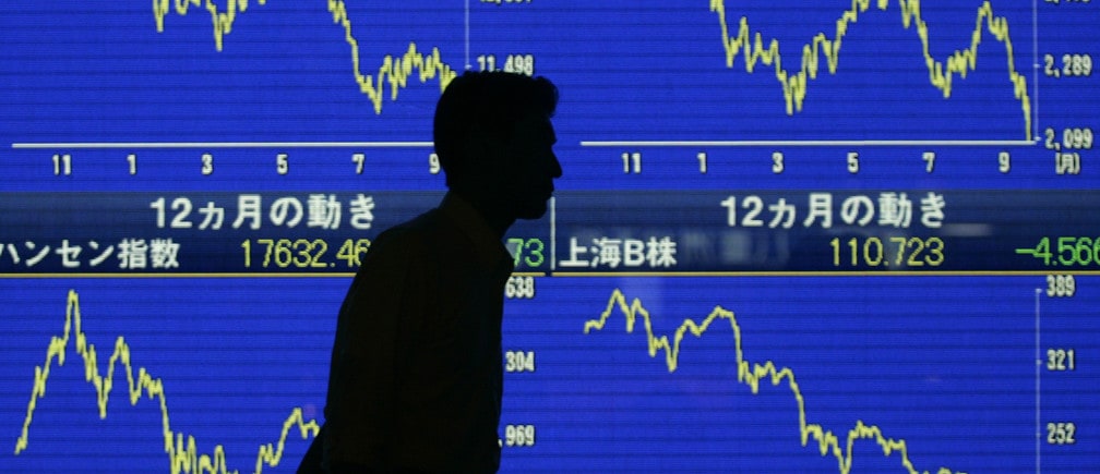 A man walks past a board displaying financial information in Tokyo September 18, 2008. The Nikkei average slid 2.2 percent to a three-year closing low on Thursday, dragged down by financial shares on renewed credit fears, as major U.S. banks scrambled for merger partners. REUTERS/Yuriko Nakao (JAPAN) - GM1E49I1GDY01