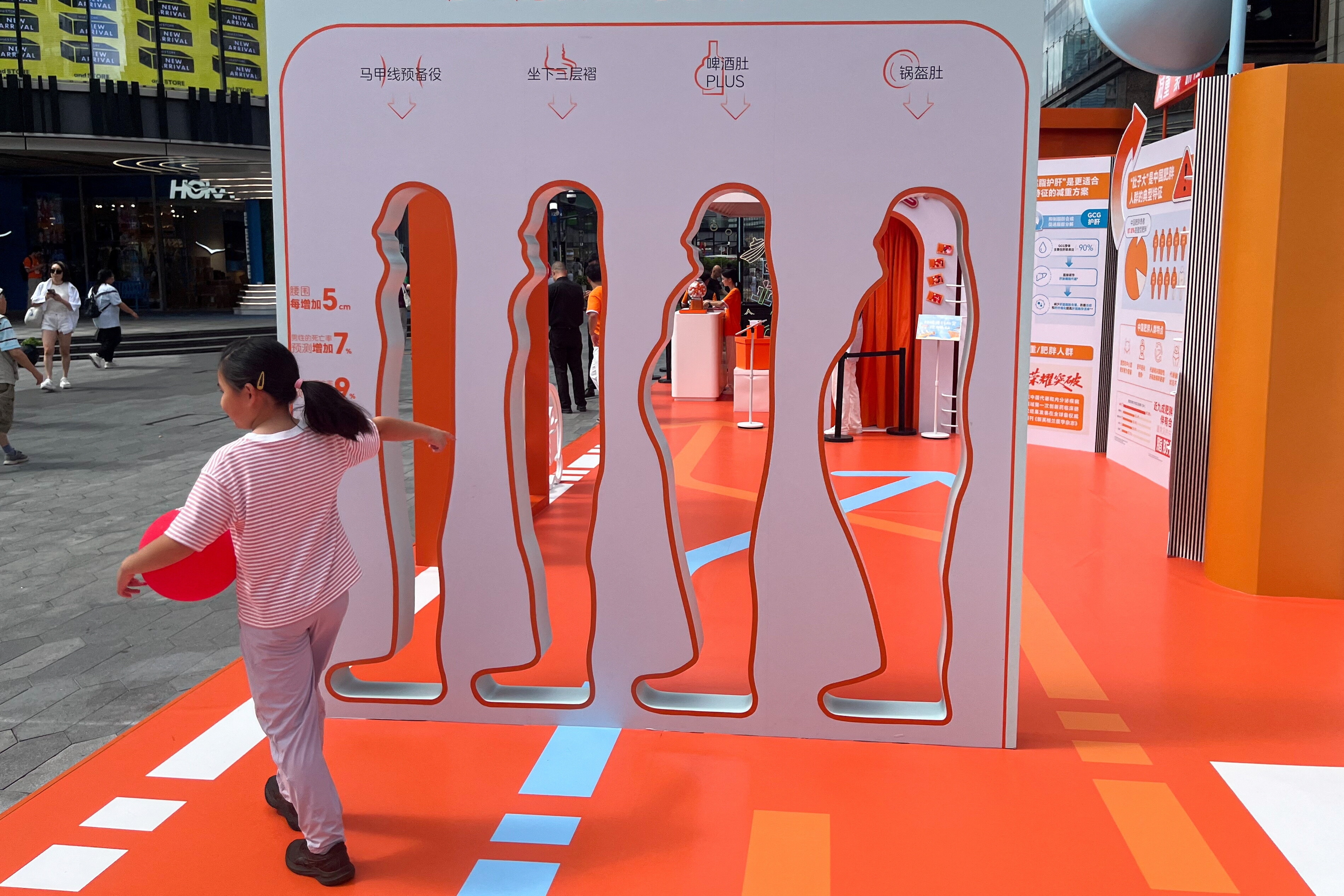 A person walks past cutout silhouettes showing different body shapes at an exhibition on abdominal obesity among the Chinese population, jointly organised by Innovent Biologics, Alibaba Health and Tmall Juhuasuan, in Shanghai, China September 22, 2025. REUTERS/Andrew Silver. metabolic health