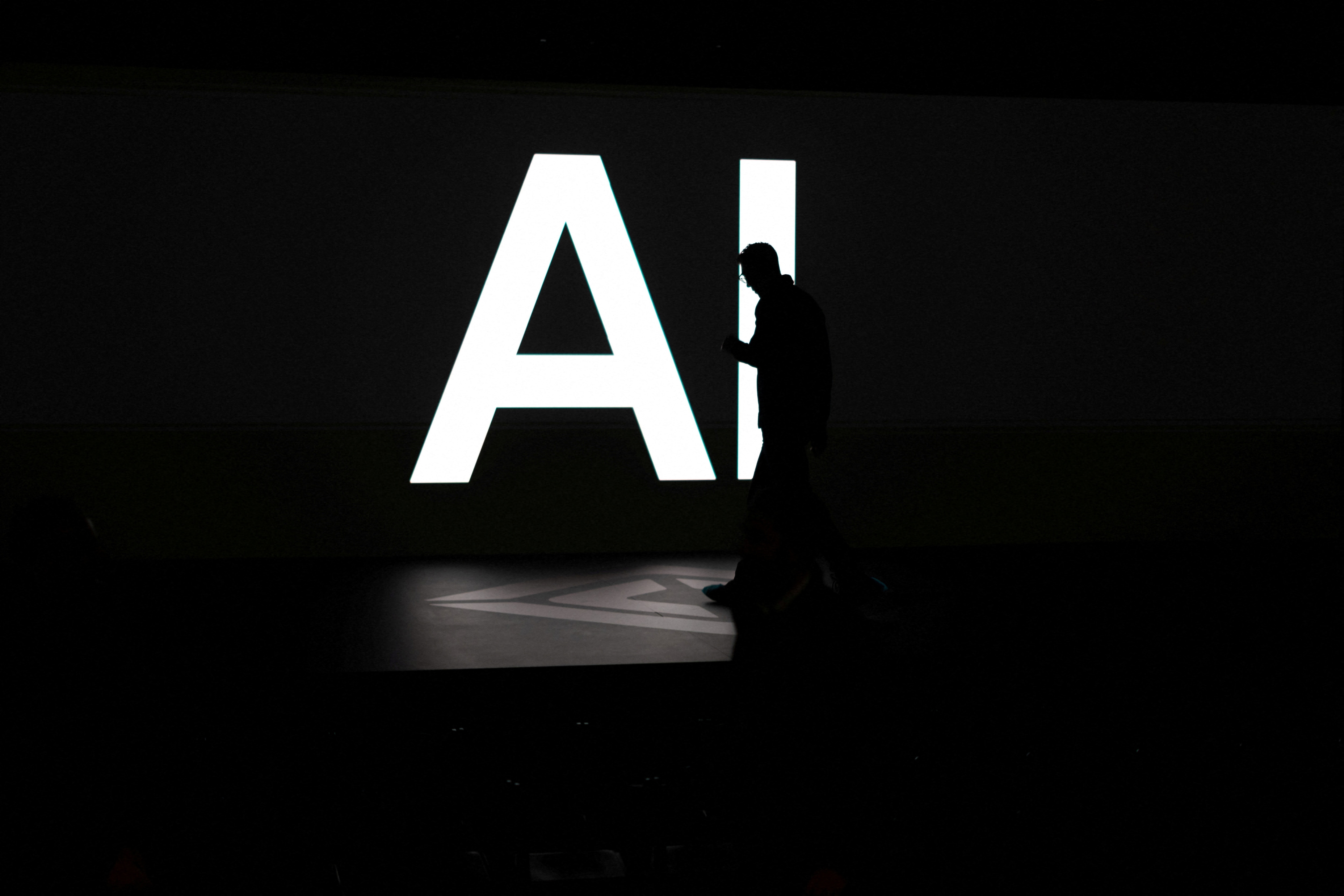 A screen displaying the letters “AI” as attendees gather at Rivian’s Autonomy and AI Day in California, US.