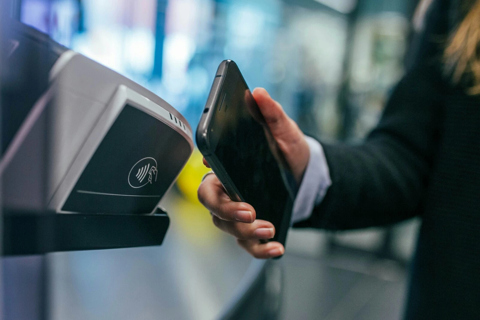 A lady holds her mobile phone up to a "tap and pay" machine.