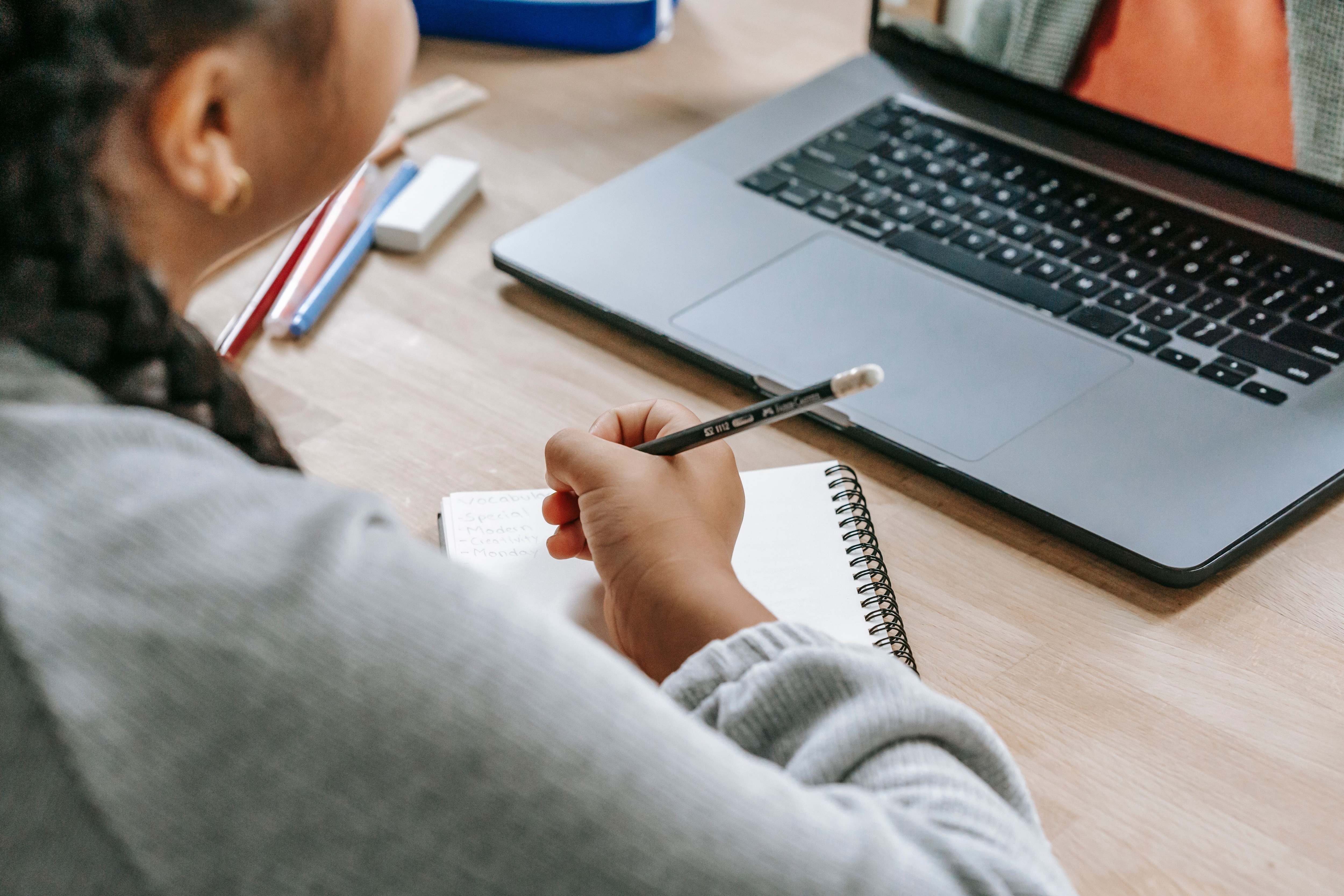 A girl looks at a computer with a notebook: Is AI in the classroom replacing the teacher as unquestioned authority?