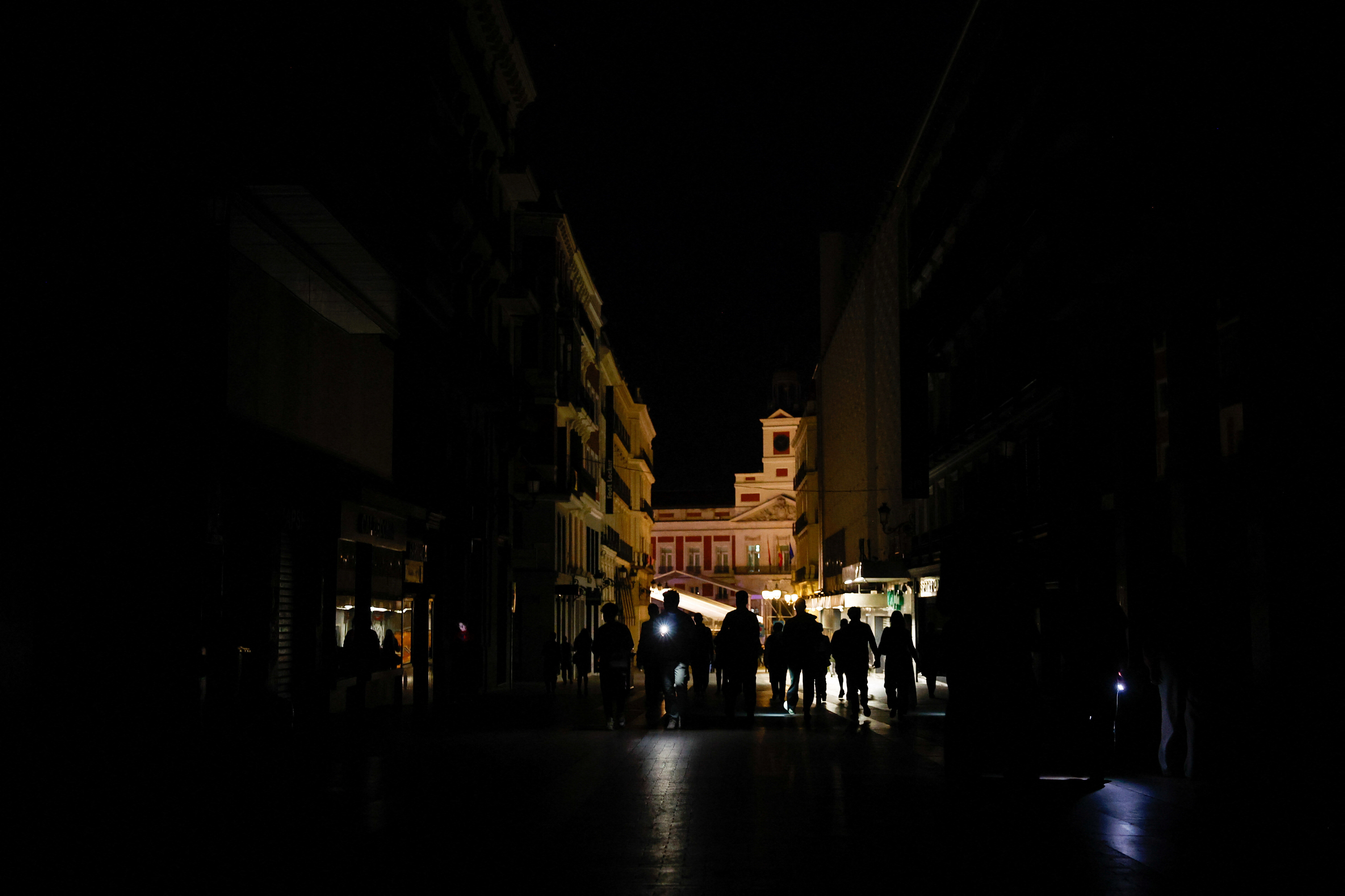 People use their mobile phone's flashlights to walk in the dark during a nationwide power outage in downtown Madrid, Spain, April 28, 2025. REUTERS/Susana Vera