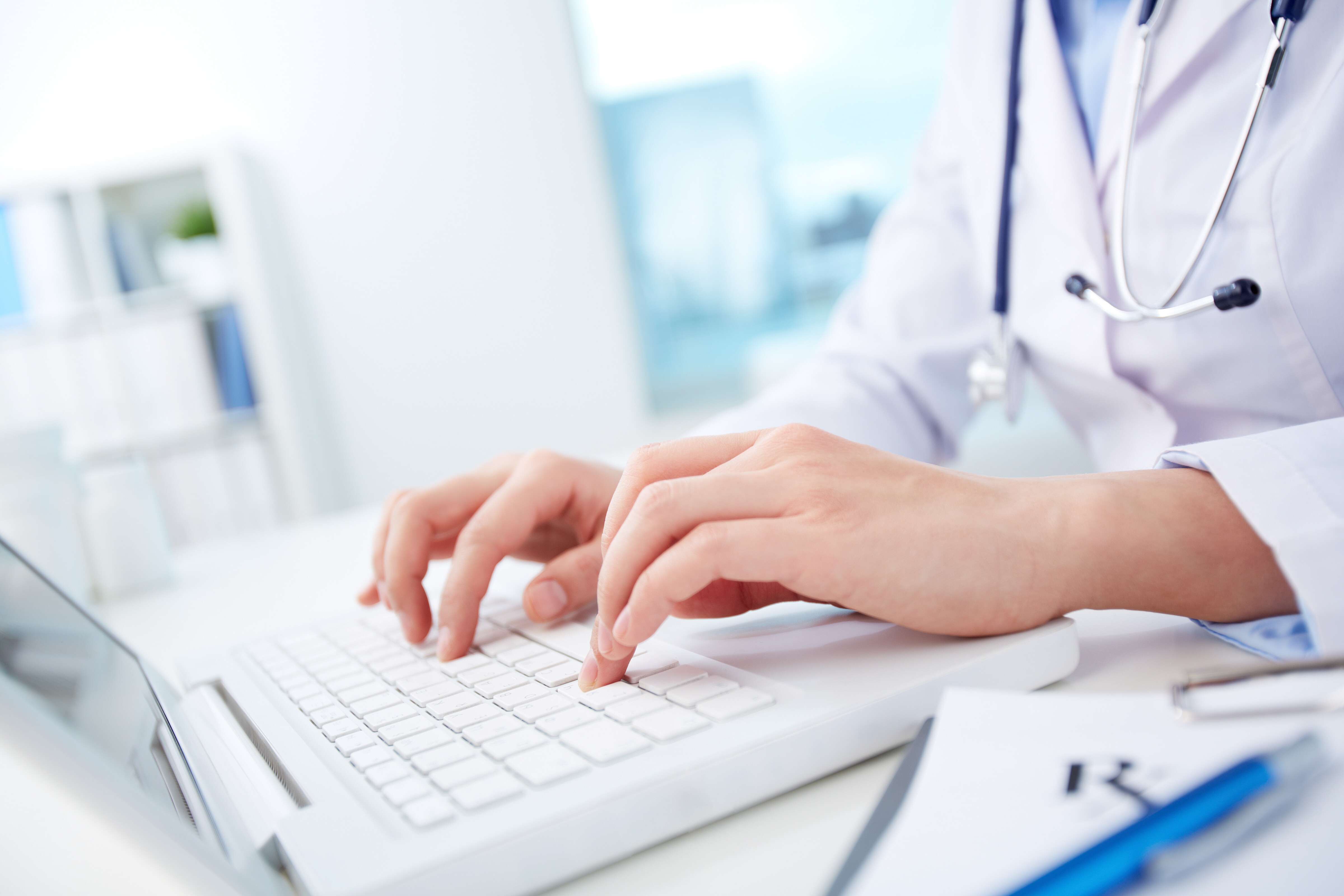 Close-up of hands of a nurse typing on laptop; influenza vaccine rates