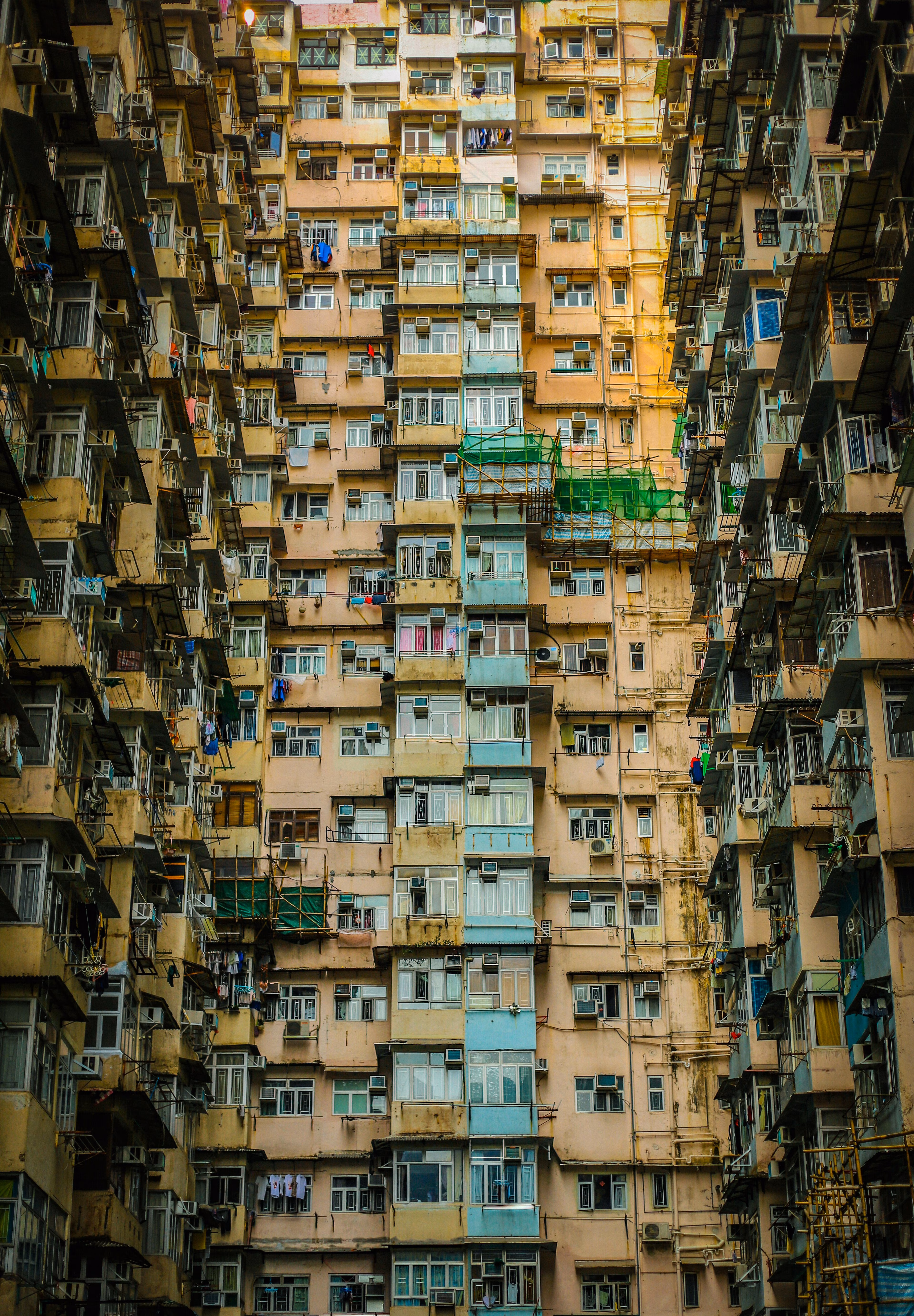 Fotografía en ángulo bajo de edificios de viviendas sociales de color amarillo, azul y topo: La escasez de vivienda se concentra en las zonas urbanas.