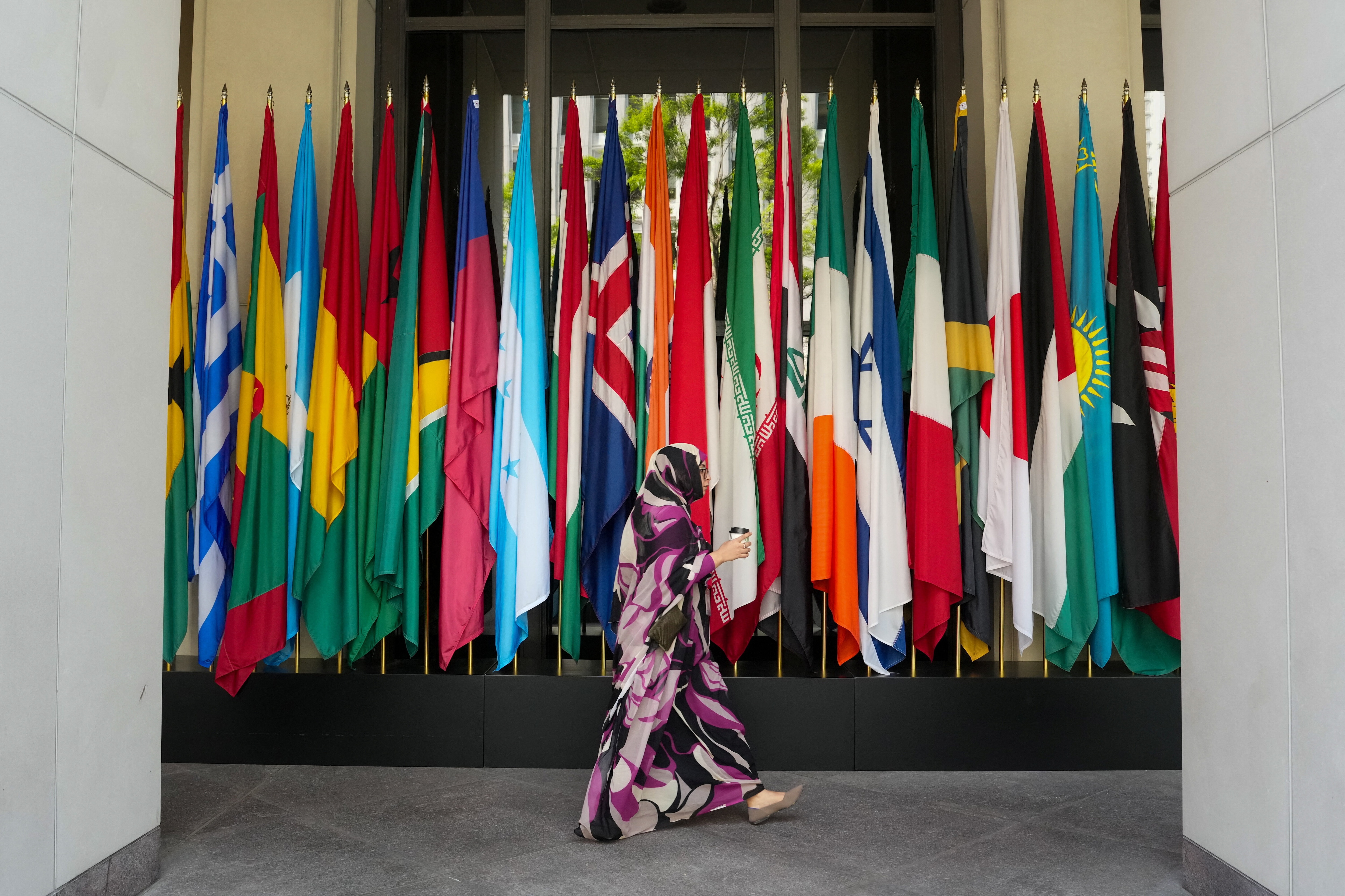 A woman walks by a long row of flags at the IMF building during the 2026 annual IMF/World Bank Spring Meetings in Washington, D.C., US, April 16, 2026.