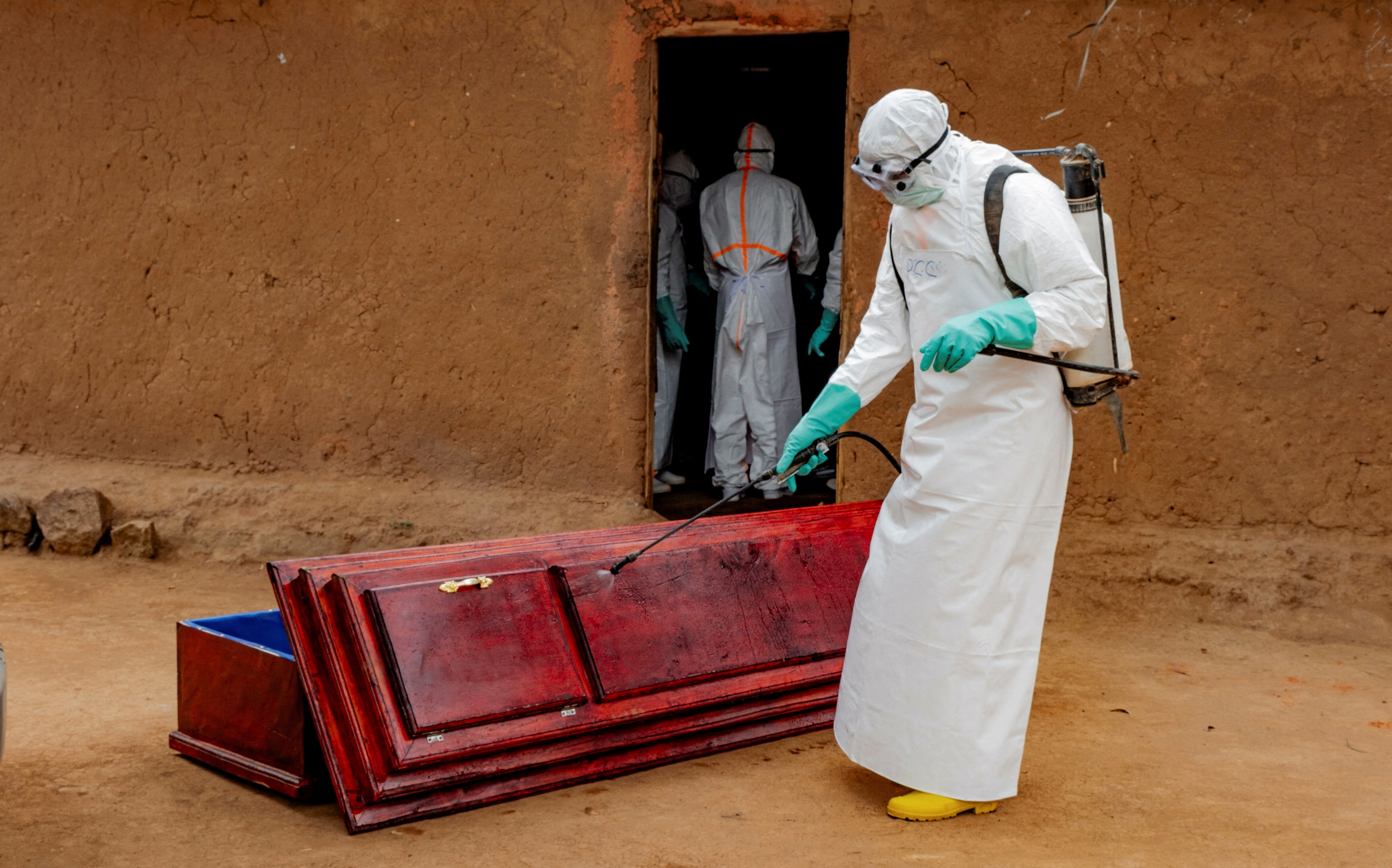 Members of the Civil Protection, a local community-based team that works to help mitigate the spread of the Ebola virus and ensure burials happen safely and quickly, wearing personal protective equipment (PPE), disinfect a wooden coffin before loading the body of an unidentified man, who according to his family, died of Ebola, as they retrieve it from his house, as aid agencies intensify efforts to contain a new Ebola outbreak involving the Bundibugyo strain, in Bunia, Ituri province, Democratic Republic of Congo
