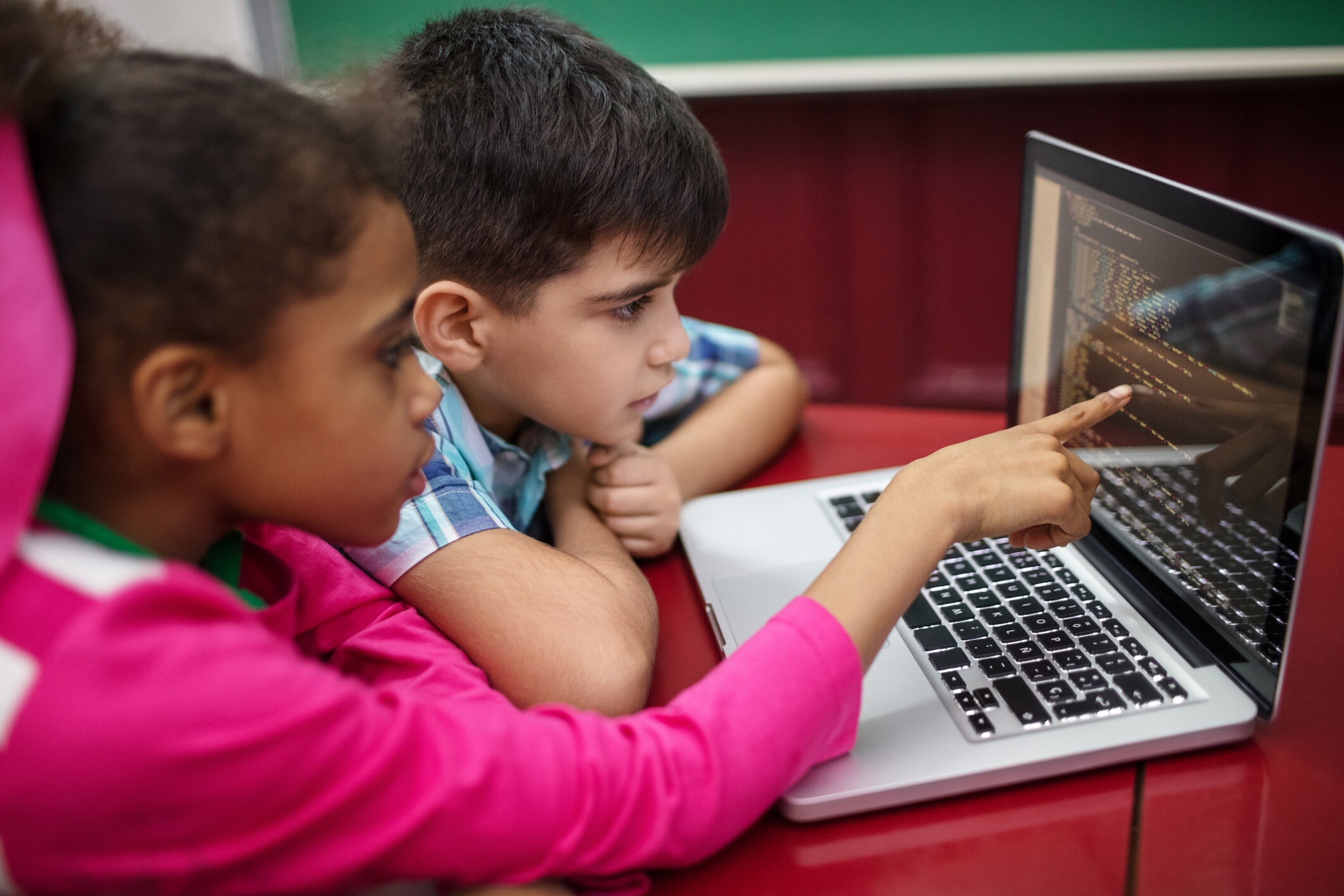 Students creating programs while using laptop. Boy and girl learning coding in school. They are at desk in classroom. AI use