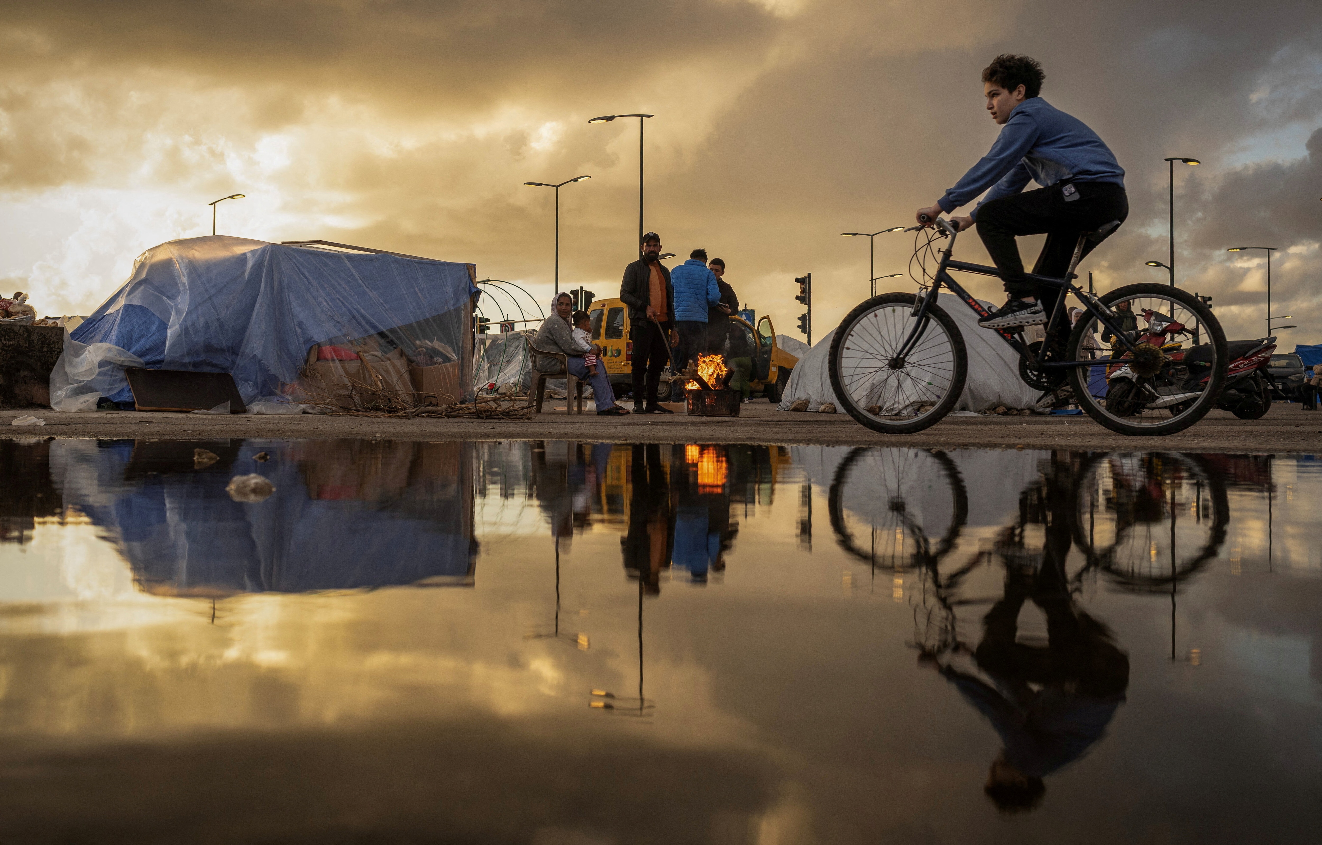FILE PHOTO: A family stand next to a fire outside their tent at a temporary encampment for displaced people, amid escalating hostilities between Israel and Hezbollah, as the U.S.-Israel conflict with Iran continues, in Beirut, Lebanon, March 30, 2026. REUTERS/Adnan Abidi/File Photo