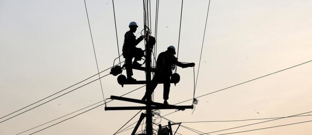 Technicians are silhouetted as they fix cables on a power transmission line in Karachi, Pakistan, January 9, 2017. REUTERS/Akhtar Soomro