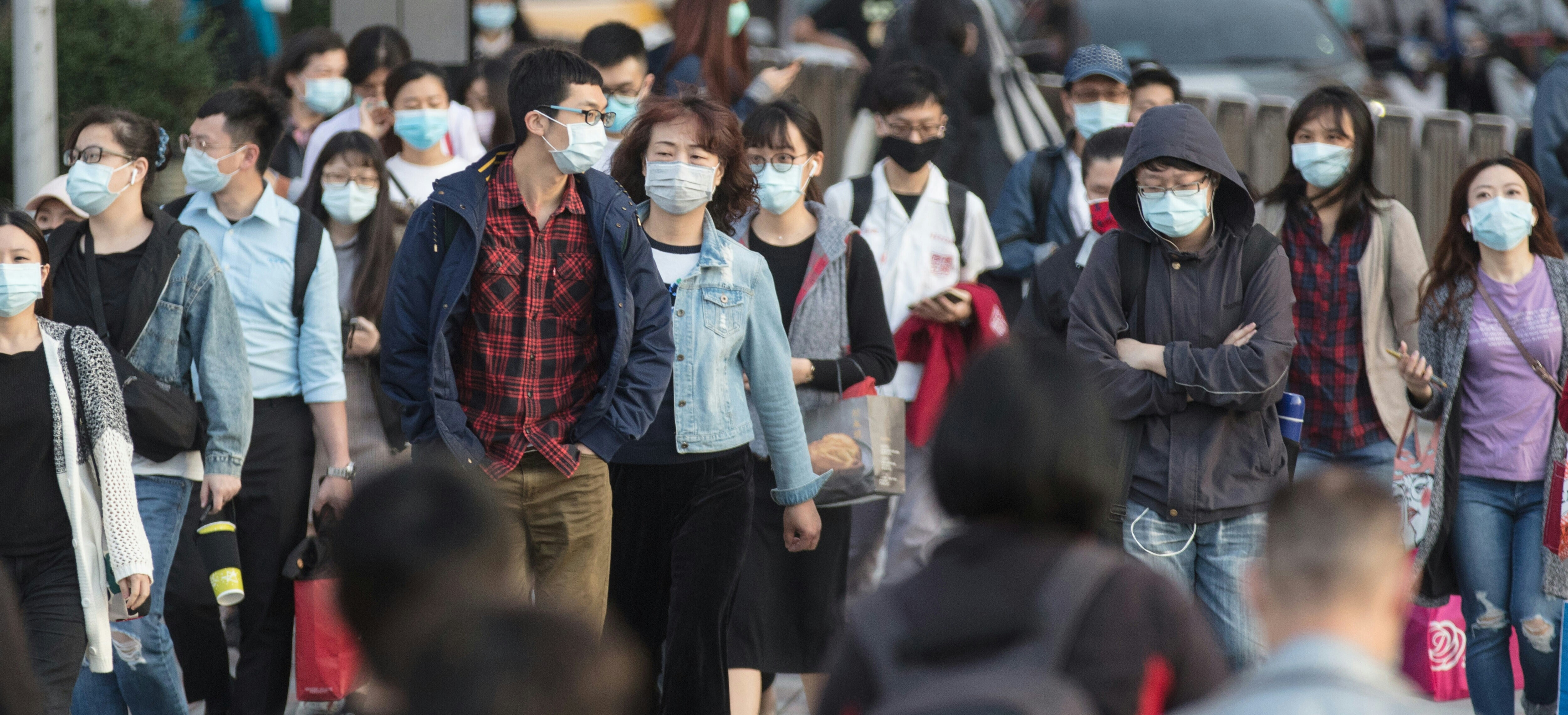 People cross a busy street wearing face masks; air pollution