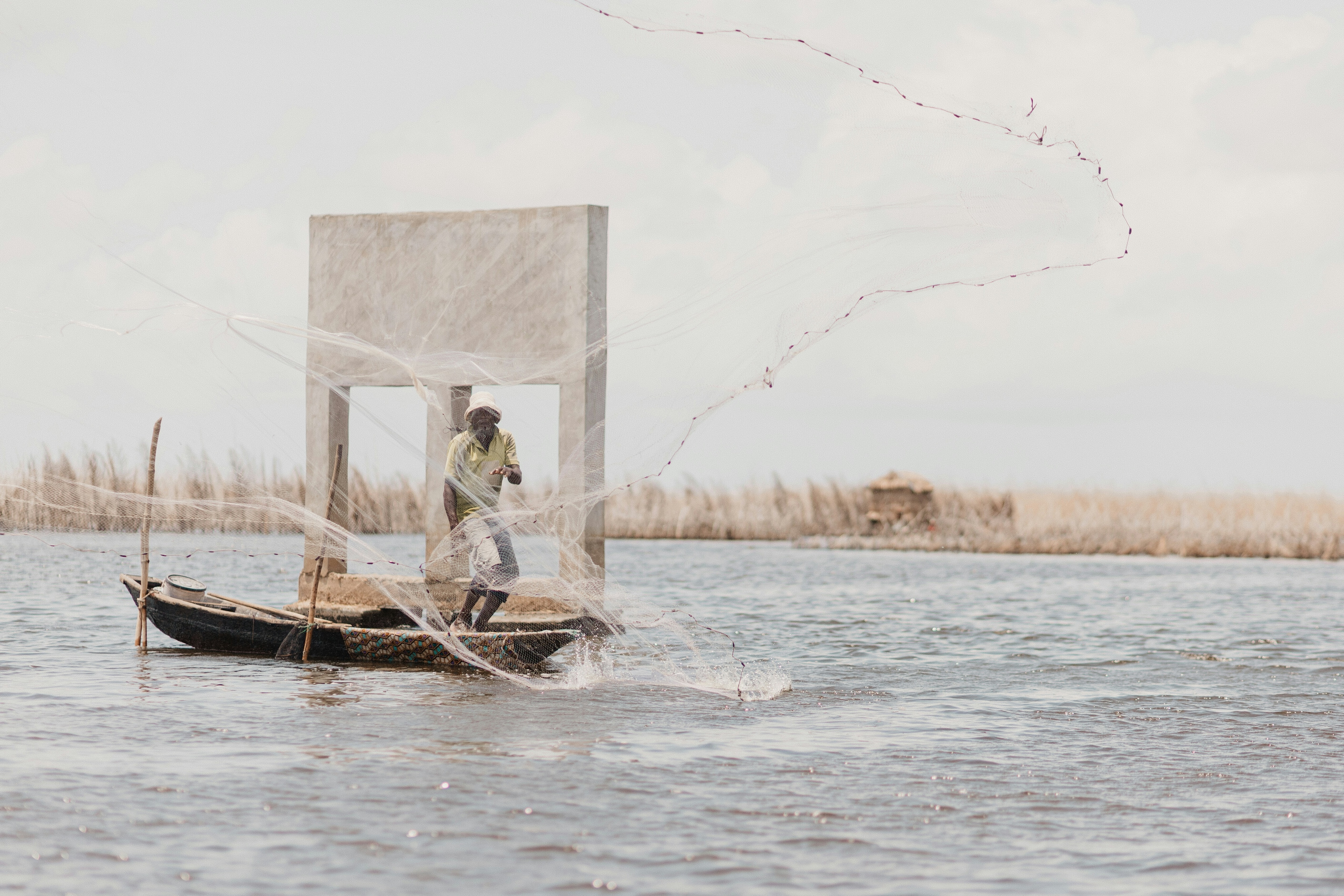 A fisherman on a small boat casts a net into the water. Doubling blue food production in Africa could reduce the per capita protein gap by about 25%, create 3 million new jobs and add about $17 billion to GDP.