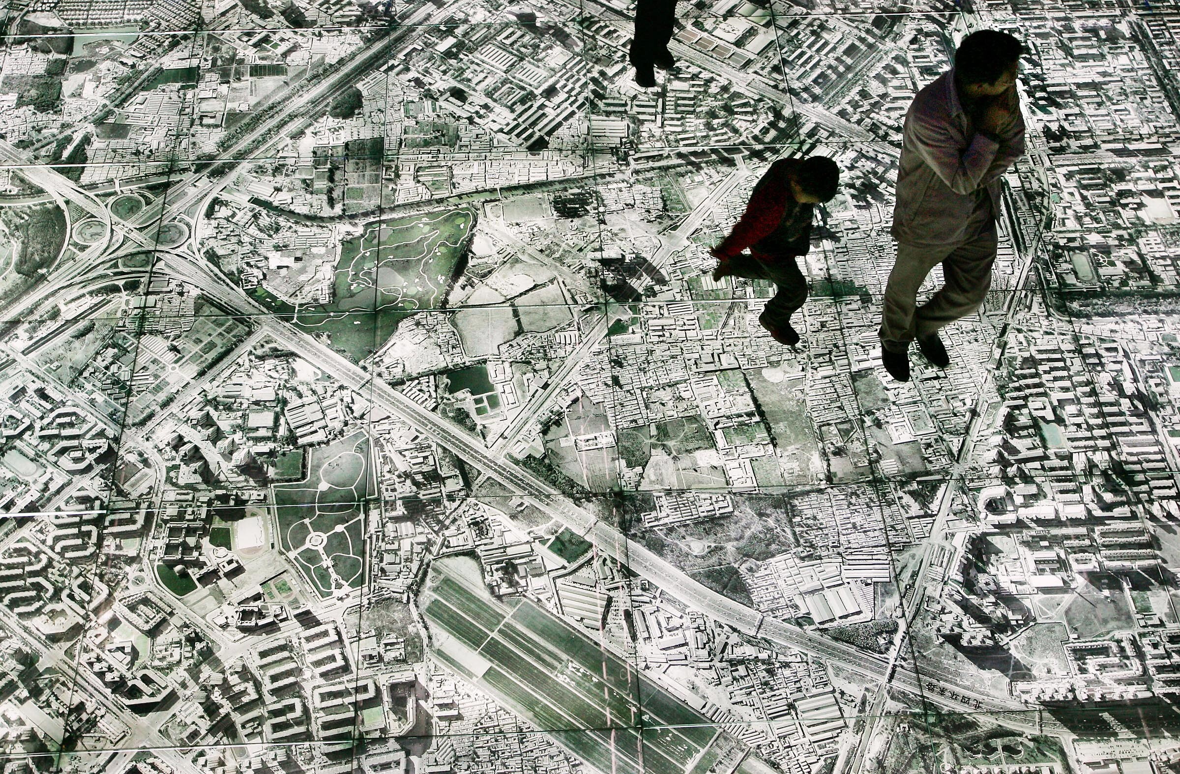Chinese vistors walk on a aerial map of China's capital including the Olympic venues at the National Exhibition Centre in Beijing October 30, 2004: Spatial data underpins logistics, urban planning, disaster response and national security