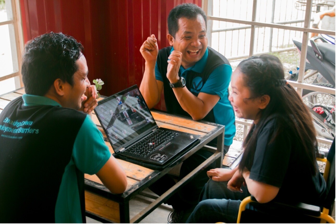 Three people in uniforms laugh; laptop, table, window. Schwab Foundation Awards