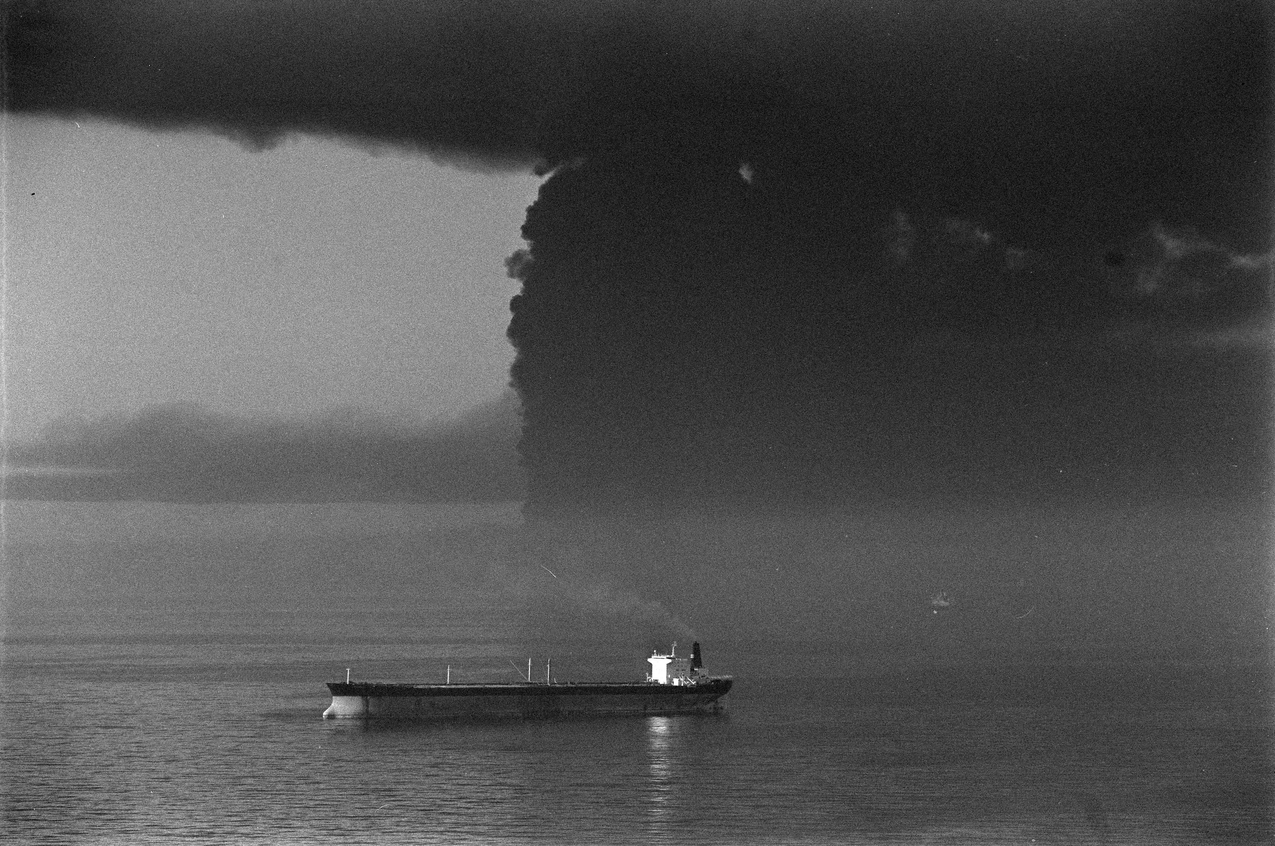 An unidentified tanker stays at anchor five miles from Larak Island near the Strait of Hormuz while a giant cloud of smoke billowed behind from four tankers, including the Seawise Giant, hit by Iraqi jets. Amid the so-called âTanker War,â when attacks on Gulf shipping and U.S. escort operations intensified in the Strait of Hormuz in the closing phase of the IranâIraq war. May 14, 1988 REUTERS/Spiros Mantzarlis 88180064