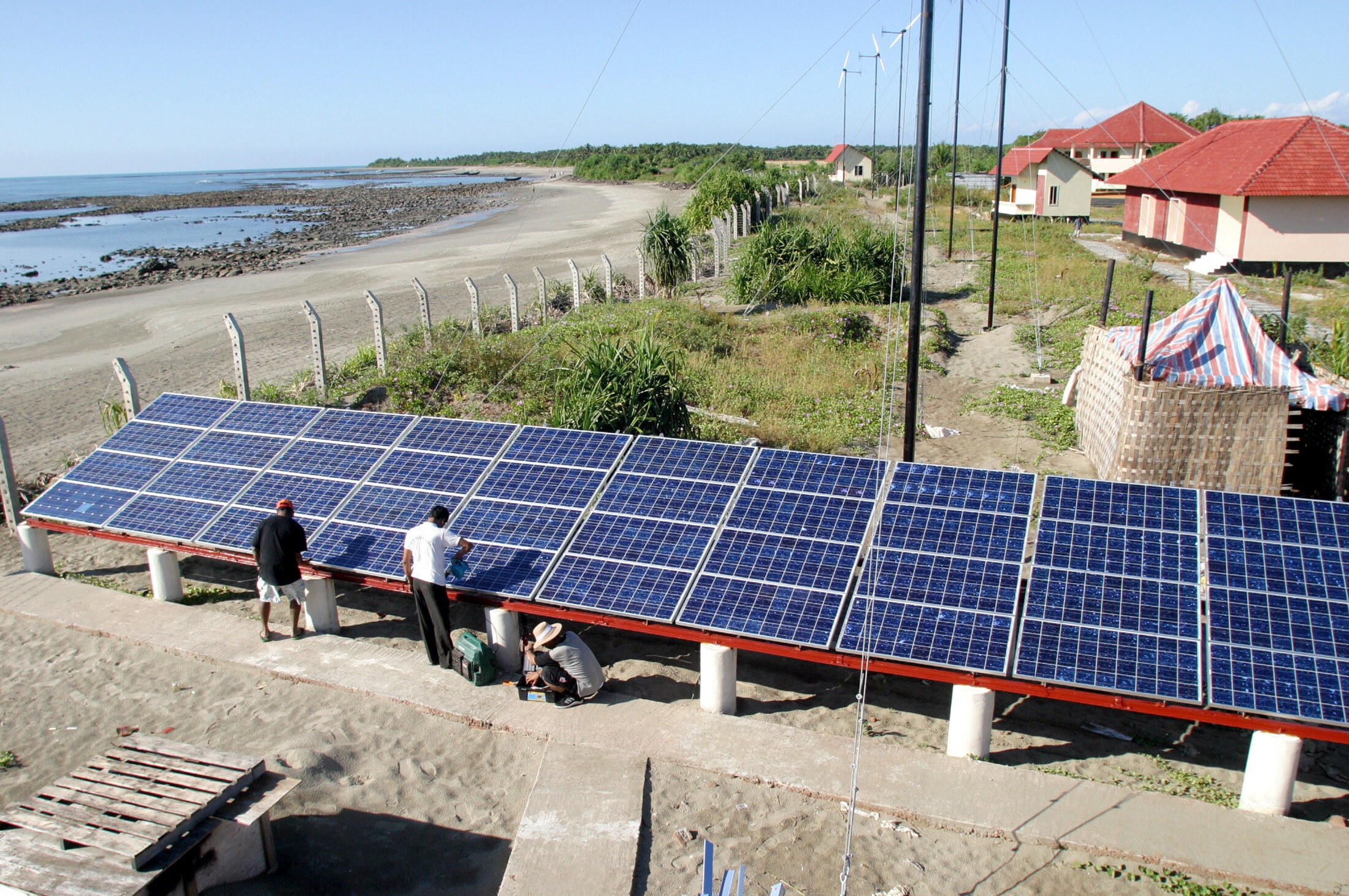 Bangladeshi experts fix a solar panel. Picture taken November 29, 2004. REUTERS/Rafiqur Rahman  RR/CN
