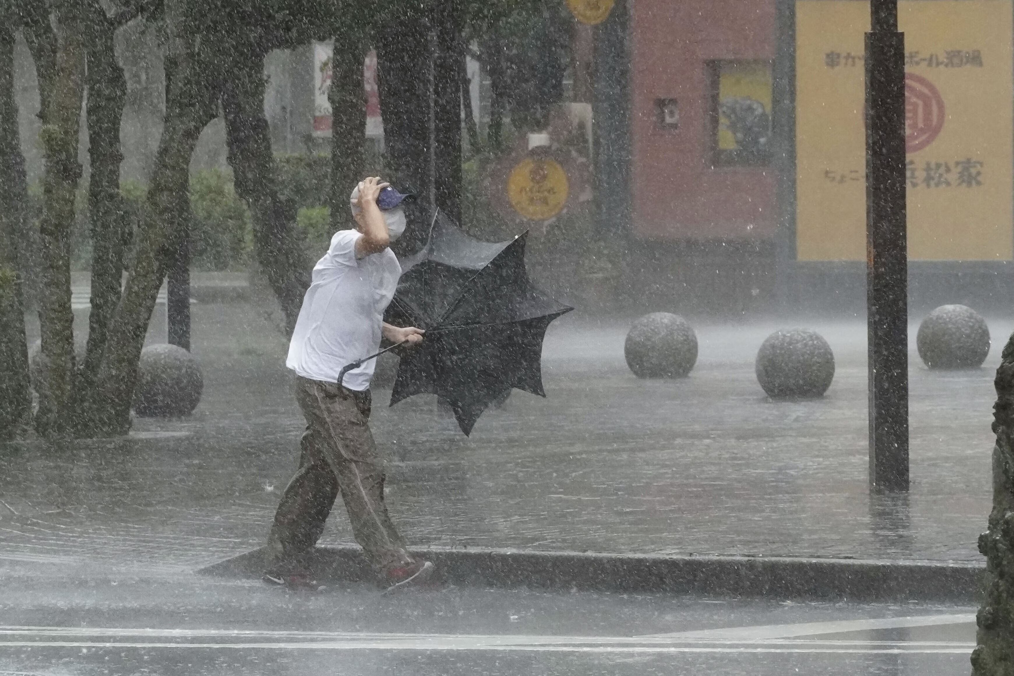 暴風雨の中、壊れた傘を手に歩く男性。日本とペルーの事例が示すように、効果的な気候変動対策は、人々の実体験と文化的価値観によって形作られます。