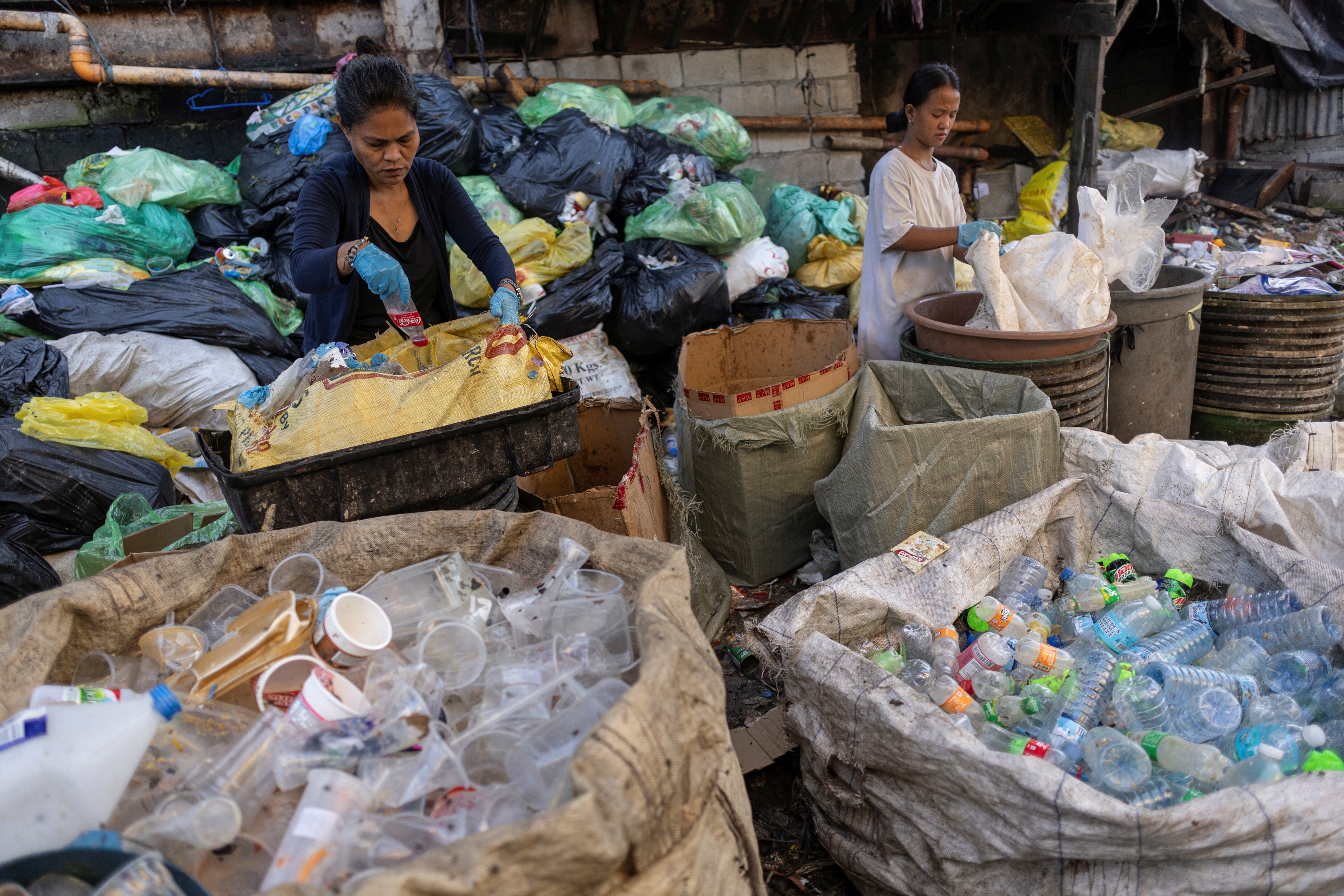 Women sort plastic bottles at a junk shop in Manila, Philippines, November 27, 2024: Communities aren't waiting for a binding treaty on plastic pollution