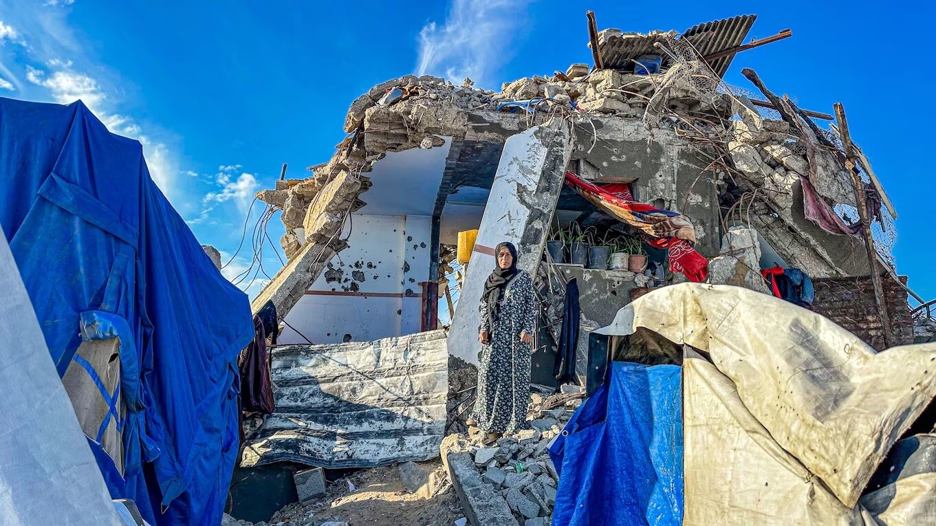 Una mujer se encuentra en medio de los escombros de un edificio destruido. Cielo azul con nubes blancas de fondo. Ayuda humanitaria.