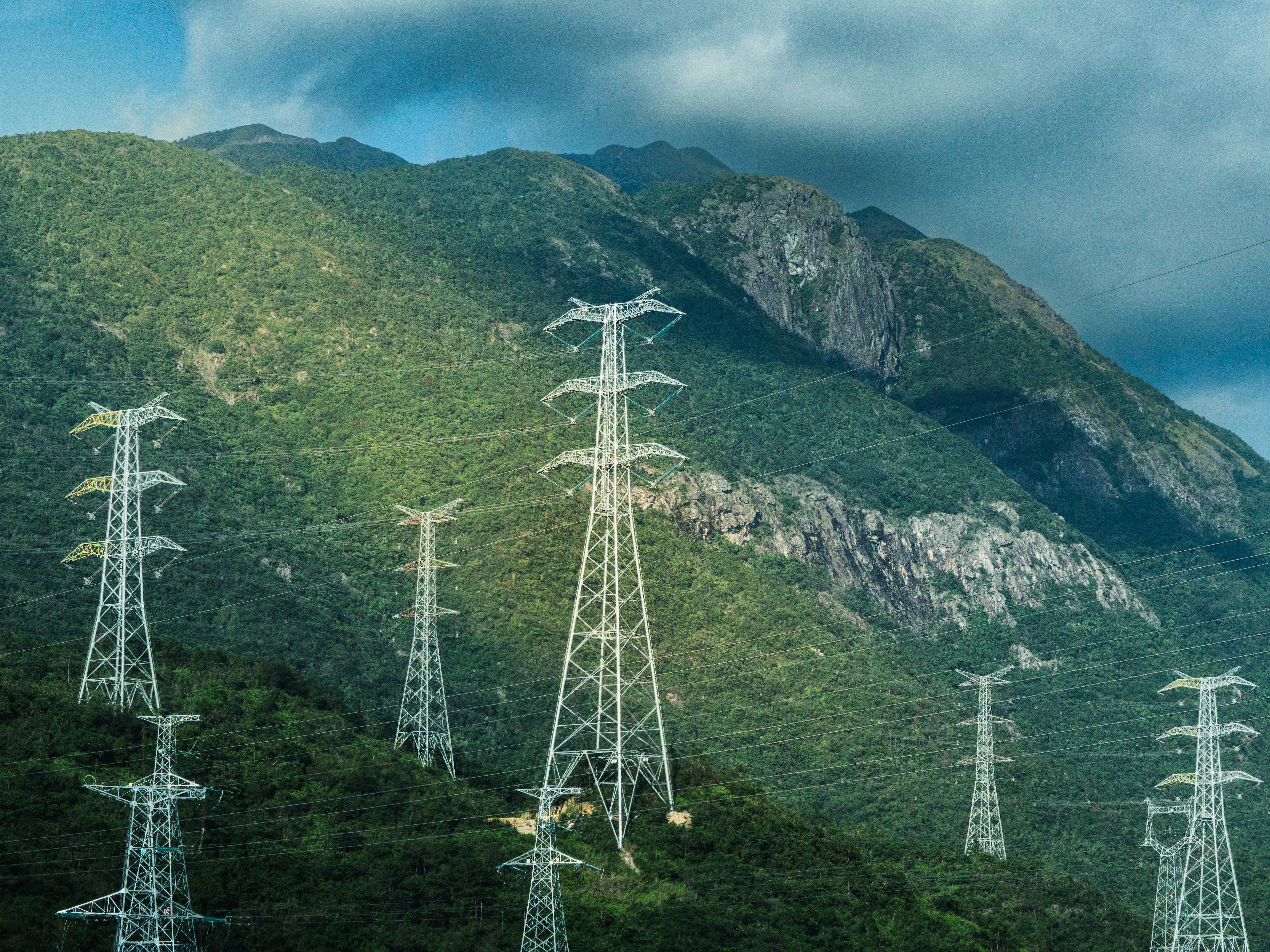 Pylons against a green mountainous backdrop in Tongxin Road, Haifeng County, Shanwei, China: Island ecosystems are pioneering the energy sector’s nature-positive transition