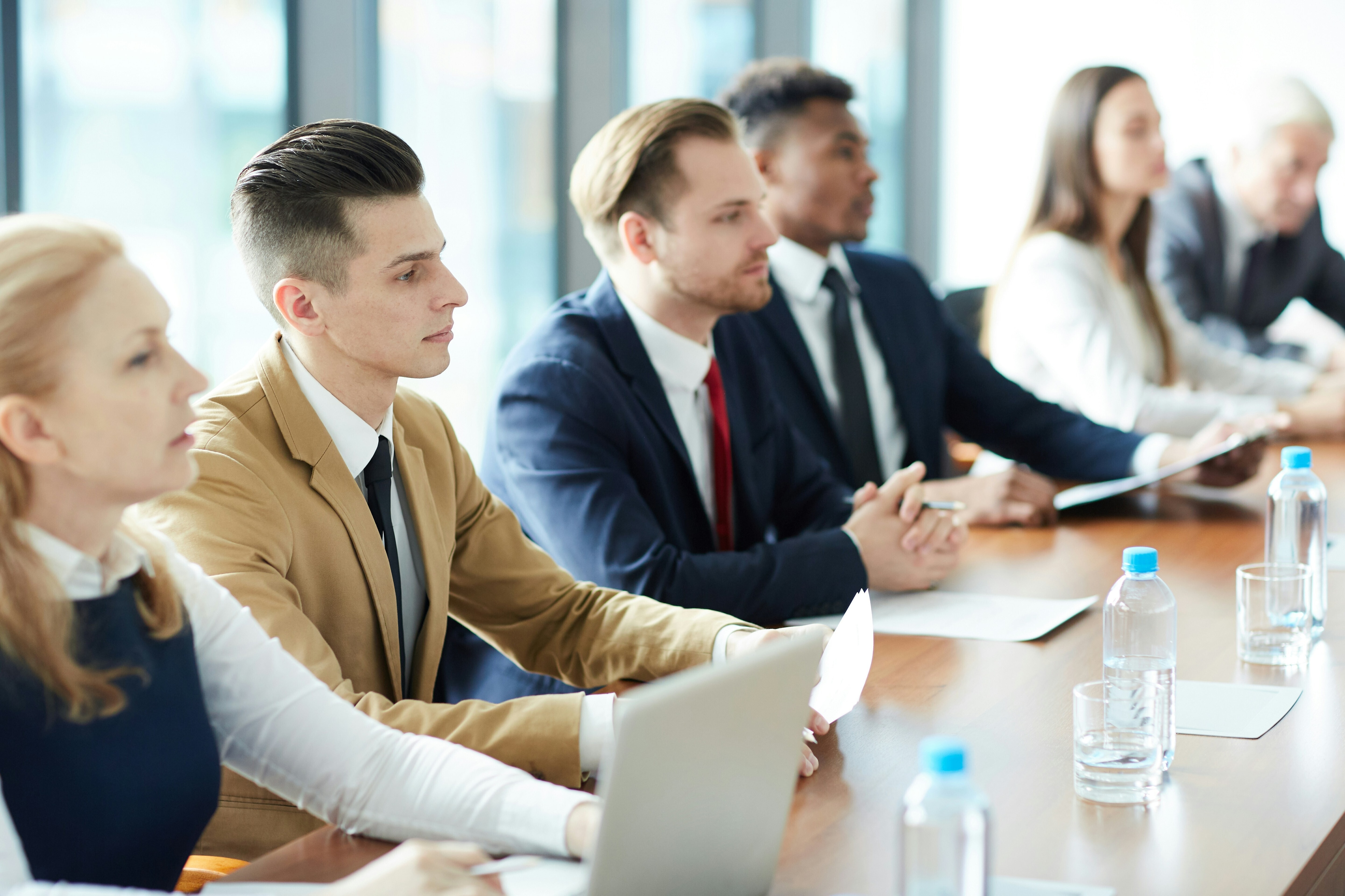 Women and men in suits sit with serious faces around one side of a board table facing another side to the table, out of view: Information security officers could try three persepectives when framing cybersecurity discussions