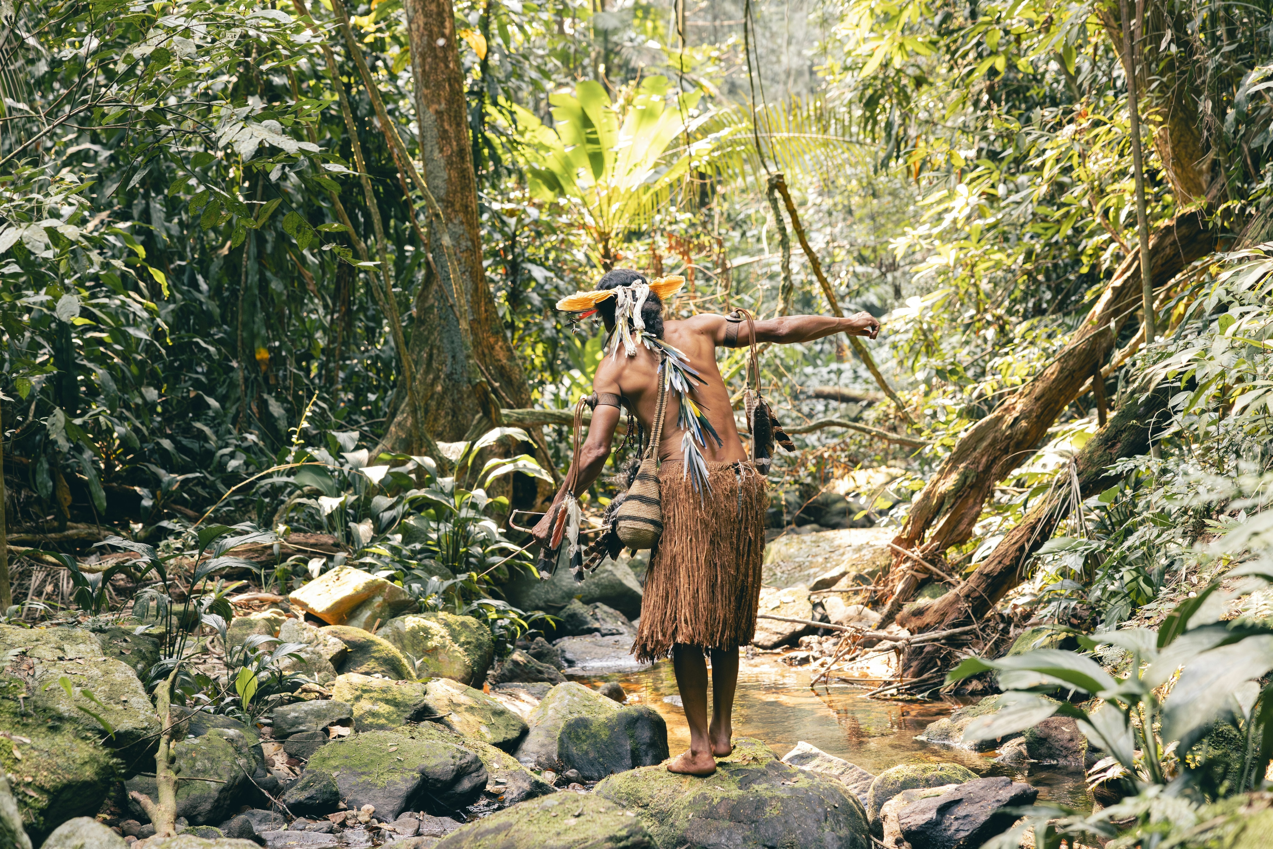 An Indigenous man in the Brazilian rainforest traverses a stream: Nature finance is far from where it needs to be