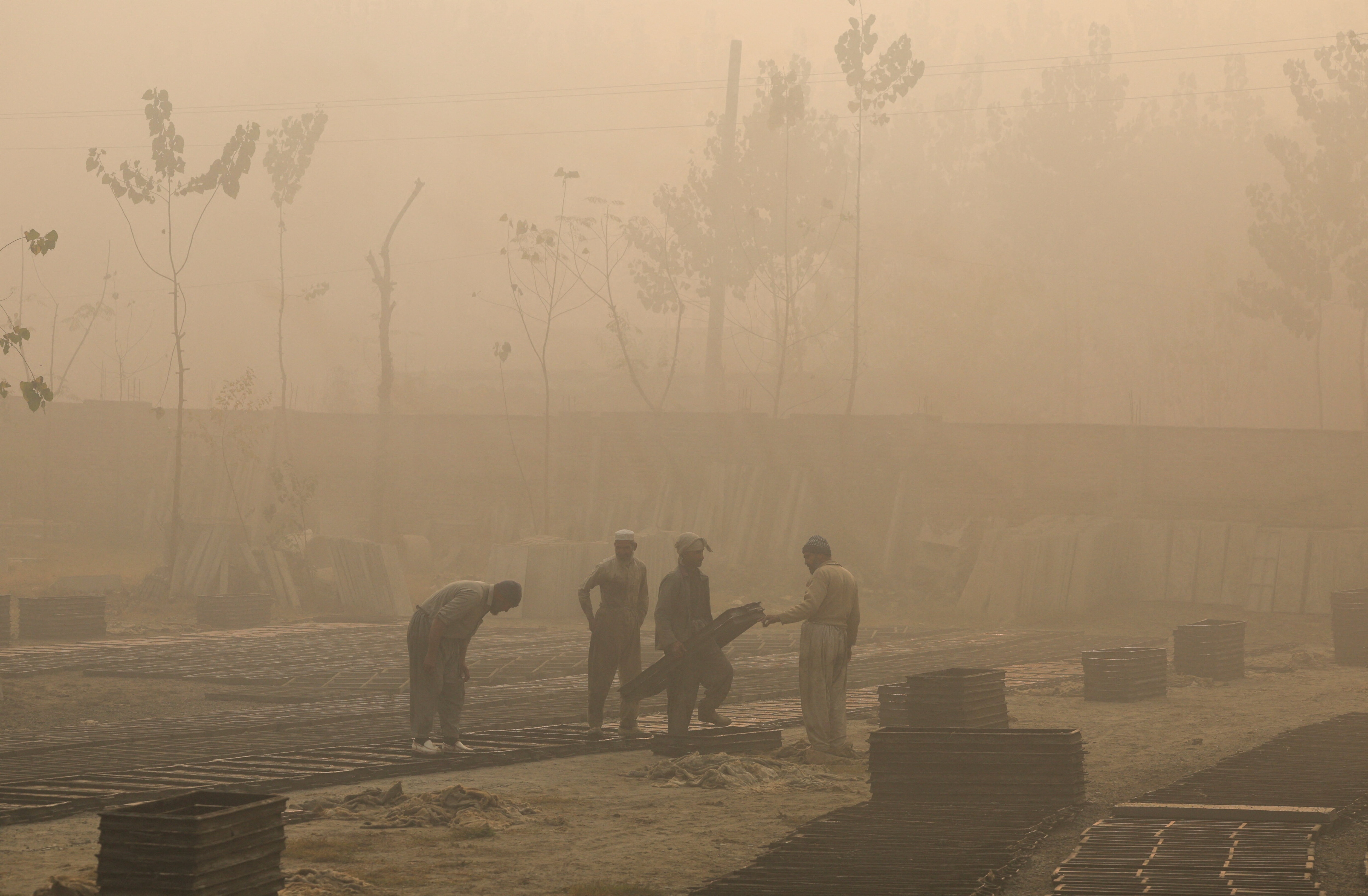 Labourers work at a brick factory during morning hours as dense smog caused by air pollution blankets Peshawar, Pakistan, December 2, 2025.